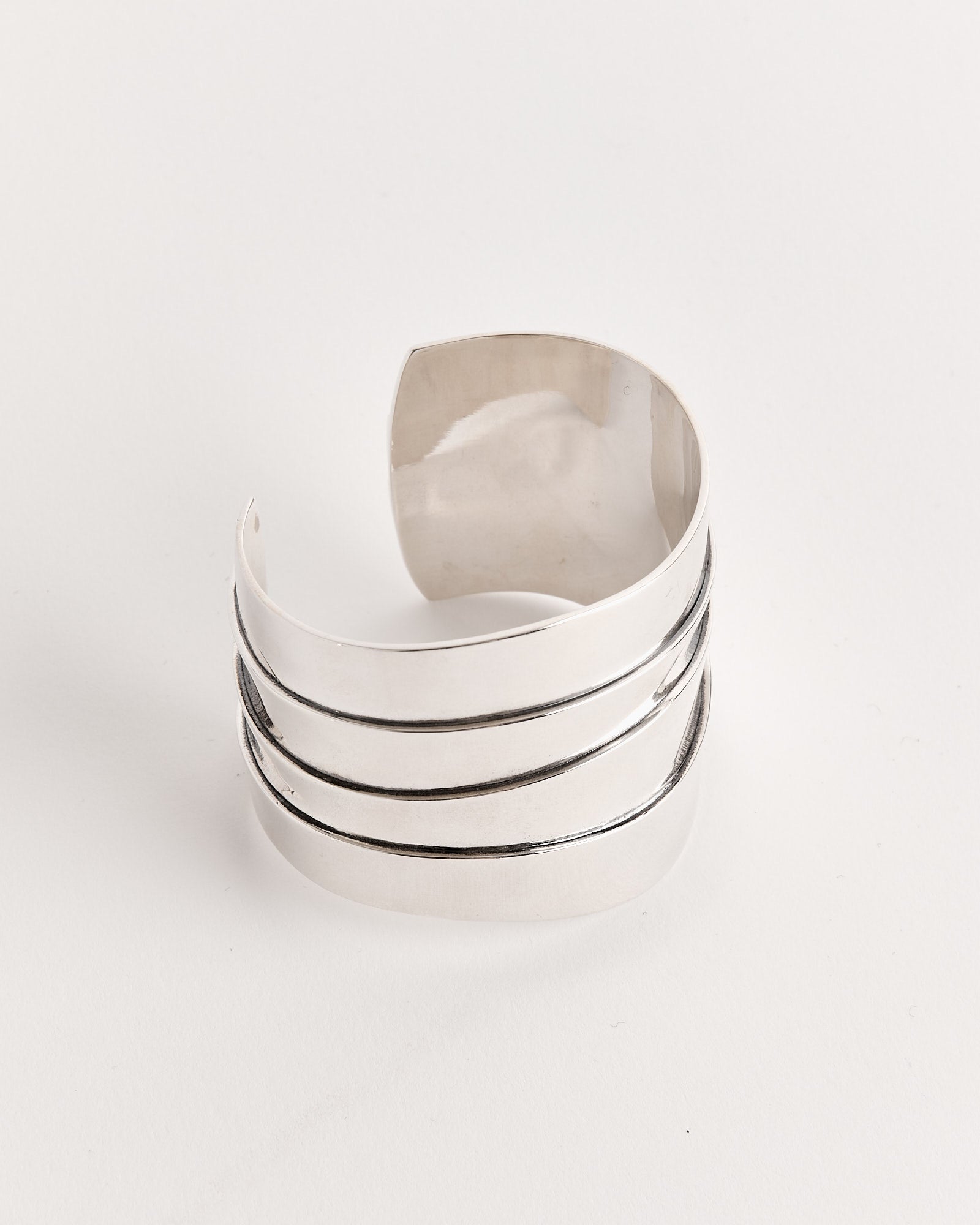 The Sophie Buhai Medium Wave Cuff in Sterling Silver features a shiny, wide design with three parallel engraved lines wrapping around its surface, shown against a plain white background.