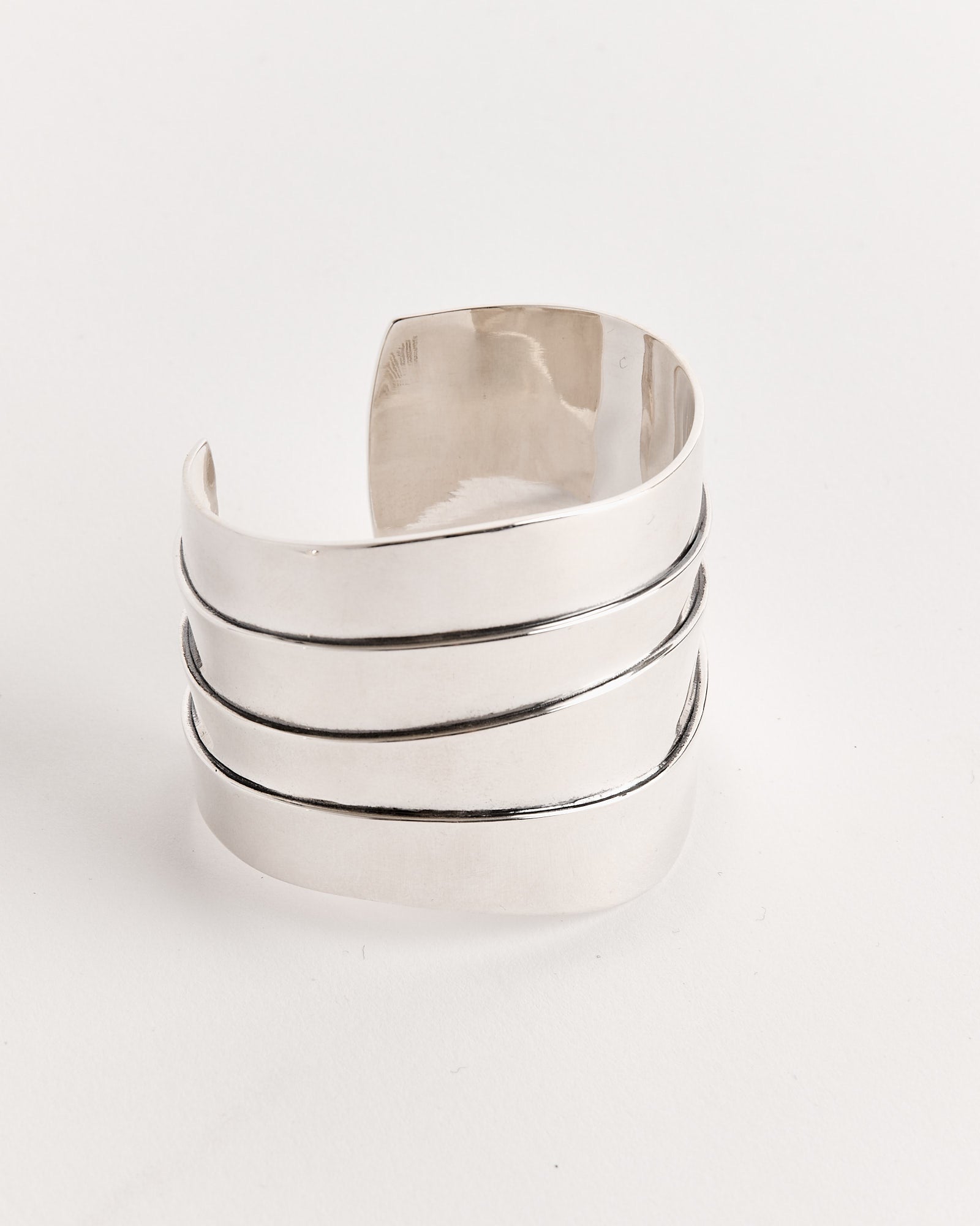 The Sophie Buhai Medium Wave Cuff in Sterling Silver features four parallel, slightly diagonal grooves wrapping around its wide, polished surface. The bracelet is displayed on a plain white background.
