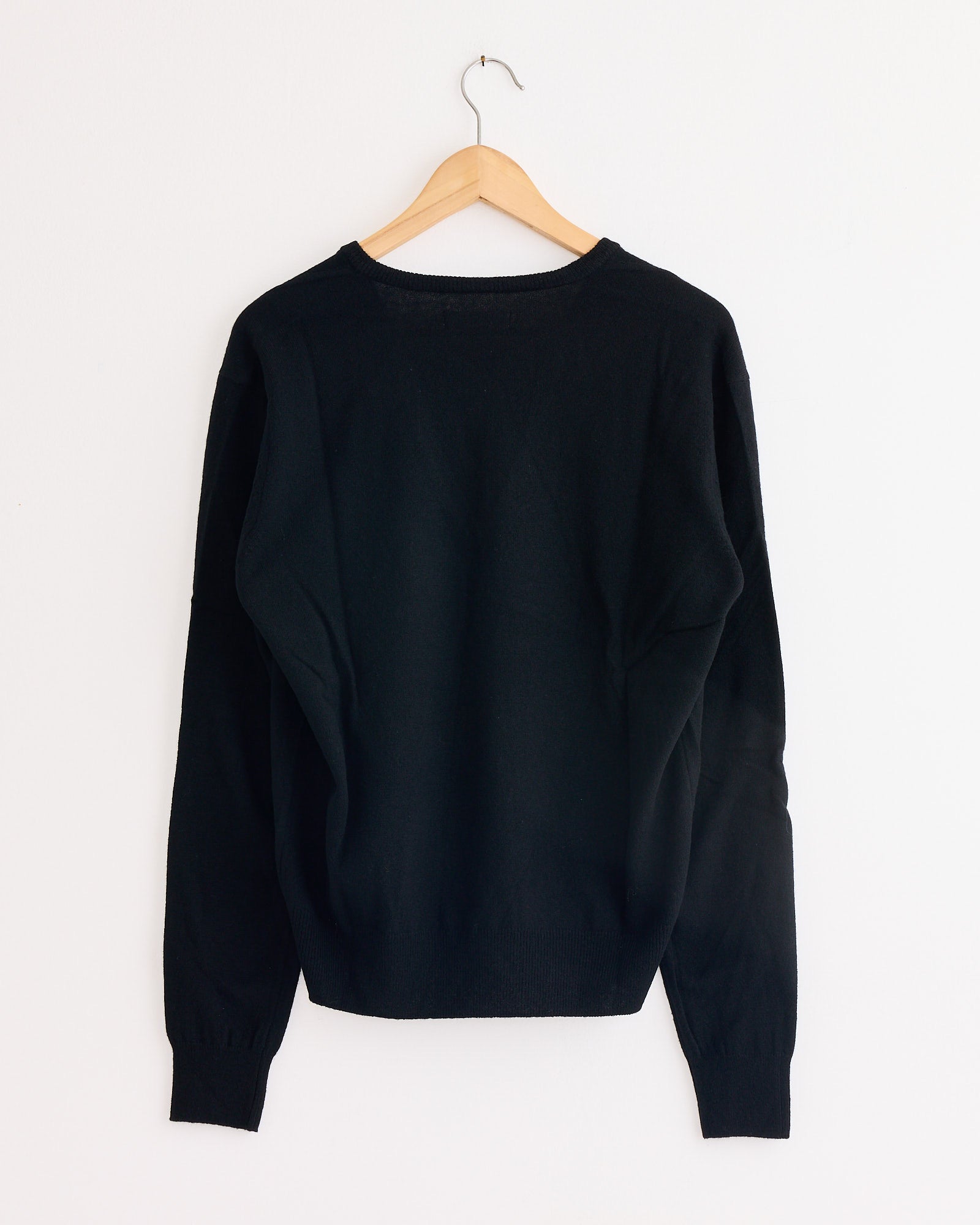 The Mijeong Park Cashmere Blend V-Neck Knit in Black is displayed from the back on a wooden hanger against a white background.