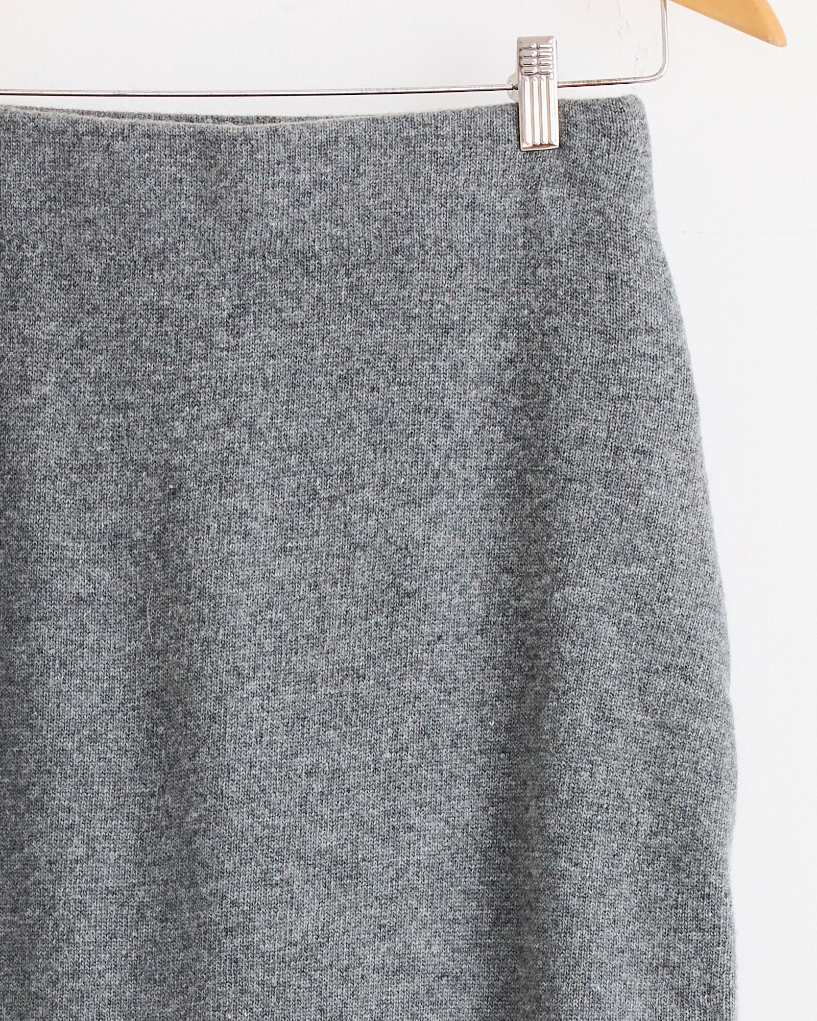 A close-up of the Mijeong Park Cashmere Blend Knit Midi Skirt in Grey, displayed on a wooden hanger against a white background.