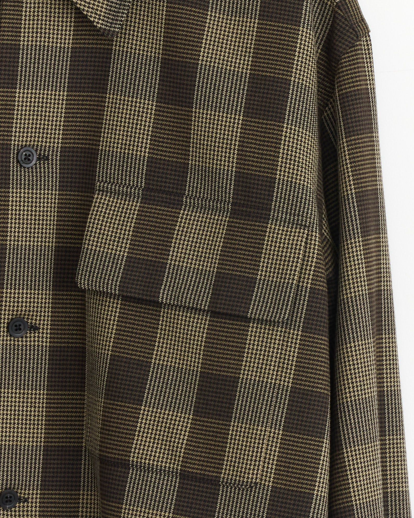 Close-up of the Margaret Howell Flap Pocket Overshirt in Black/Brown/Multi, highlighting its plaid cotton wool twill, large flap chest pocket, black buttons, and detailed checked pattern.