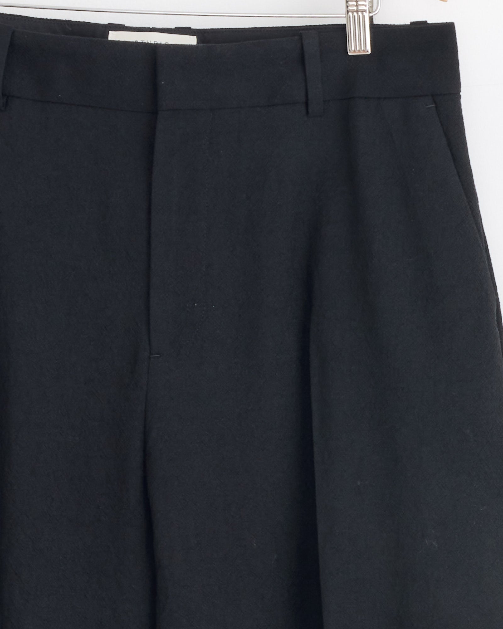 Close-up of the Studio Nicholson Fume Pant in Black, crafted from Italian-milled virgin wool, showcasing the waistband, belt loops, pockets, and front crease for a refined yet relaxed tailored look.