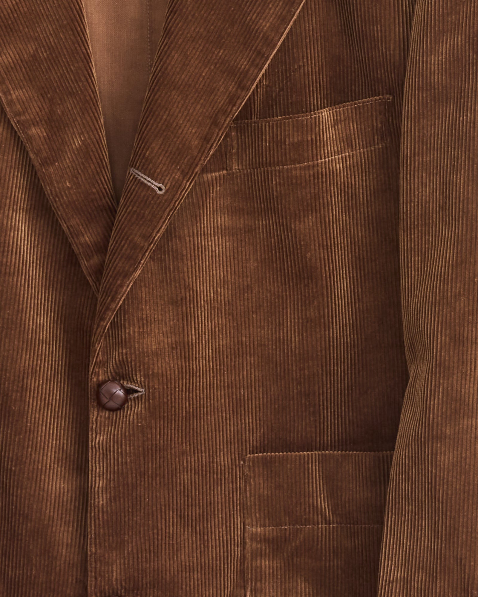 Close-up of the Studio Nicholson x BEAMS PLUS Paul Coat in Toffee, a brown corduroy blazer with textured fabric, single button, and two front pockets. Made in Japan.