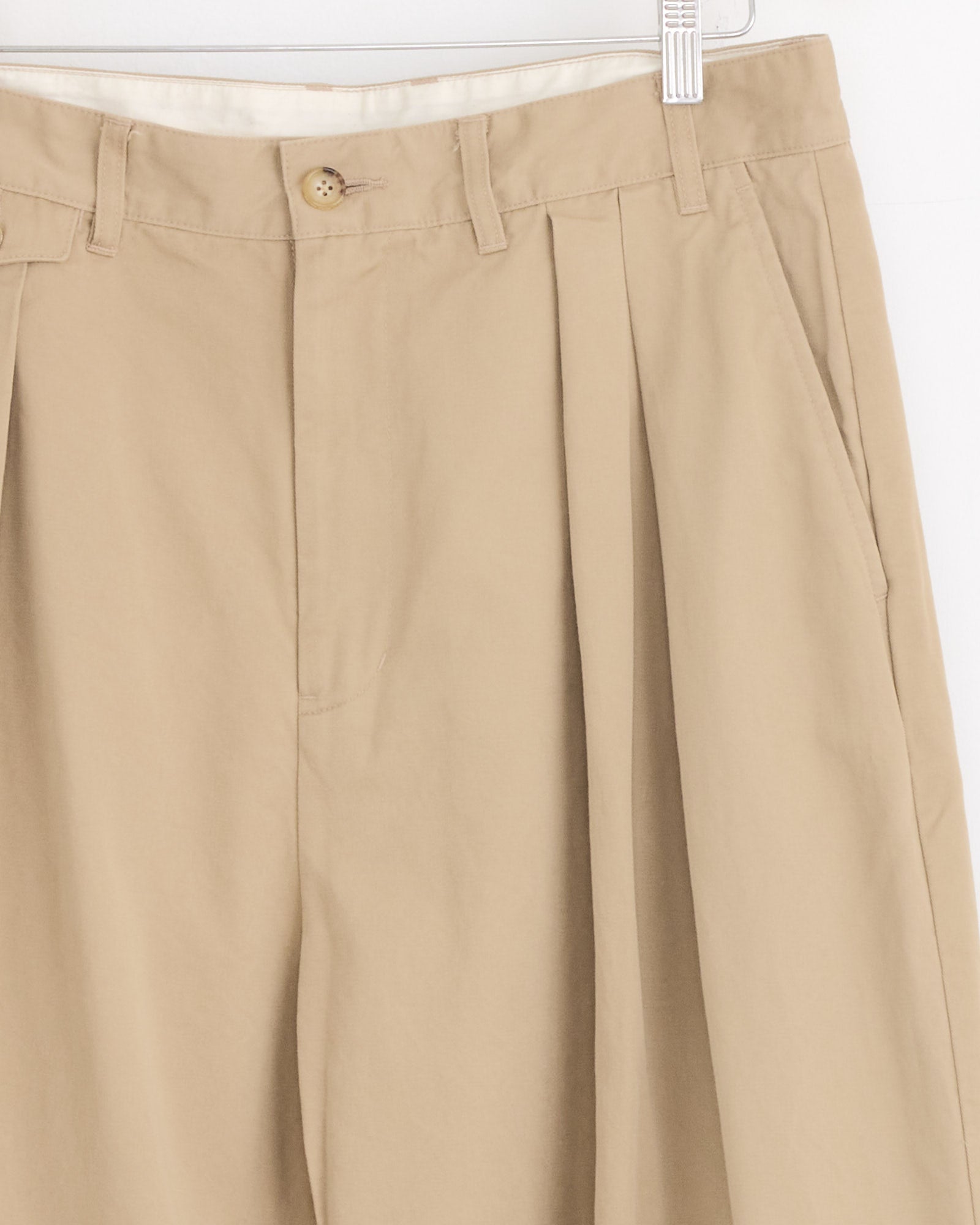The Studio Nicholson x BEAMS PLUS Alvy Pant in Tan features high-density cotton twill, pleats, belt loops, side pockets, and a button waist closure for relaxed tailoring.