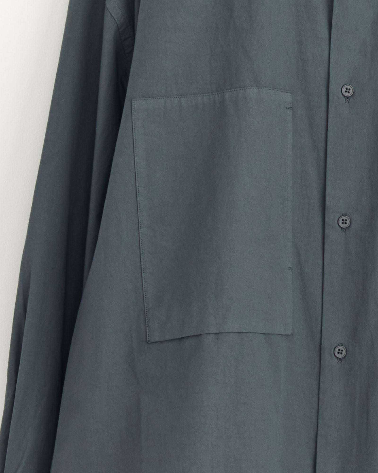 Close-up of the Still By Hand Garment Dye Over Shirt in Blue Grey, crafted in Japan from peach skin cotton, featuring a large left chest pocket and three buttons along the opening.