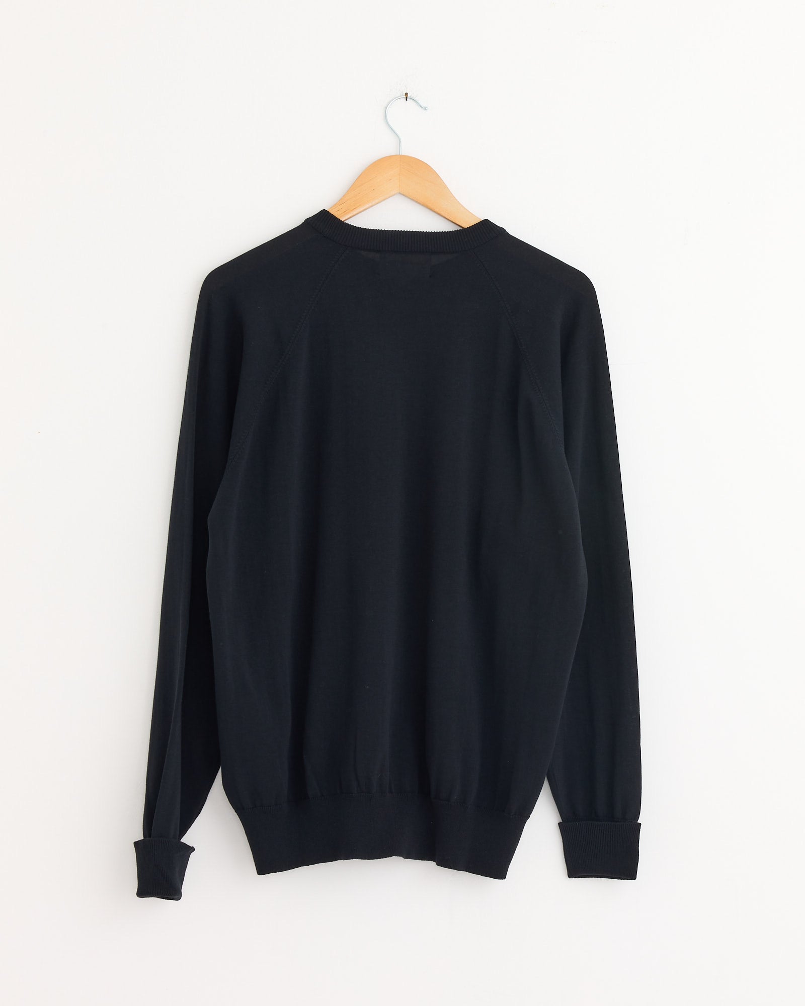 The Still By Hand Cotton Silk Pullover in Black Navy, shown from the back on a wooden hanger against a white wall. Made in Japan from lightweight cotton-silk.