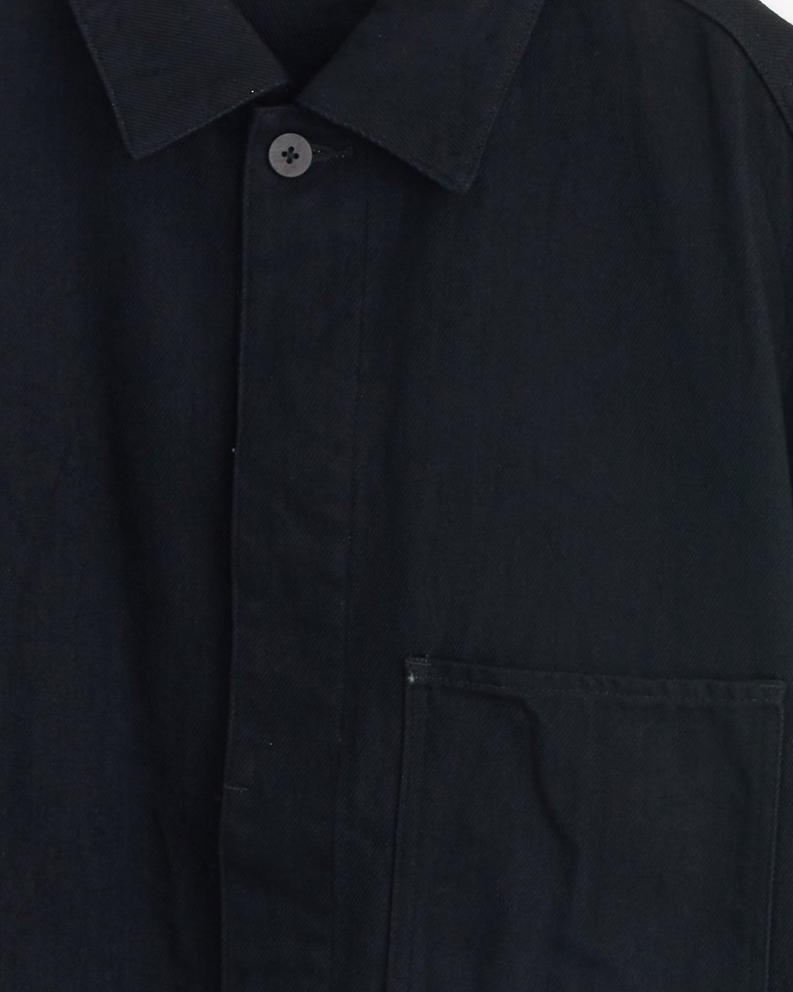 Close-up of the Still By Hand 12oz Denim Jacket in Black, made in Japan, highlighting the collar, a single button, and the right chest pocket.
