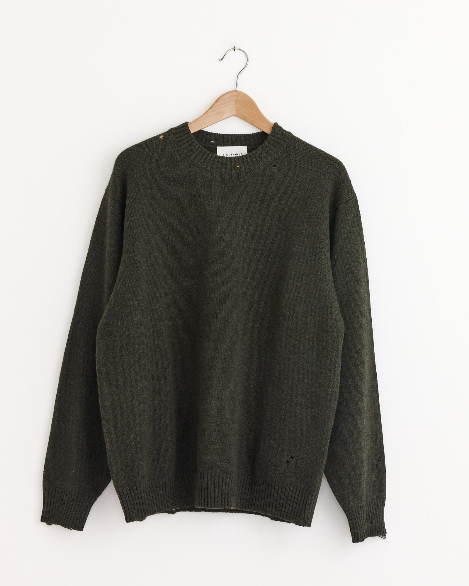The Punched Shetland Sweater in Khaki Green by Still By Hand, crafted in Japan, on a trendy swinger.