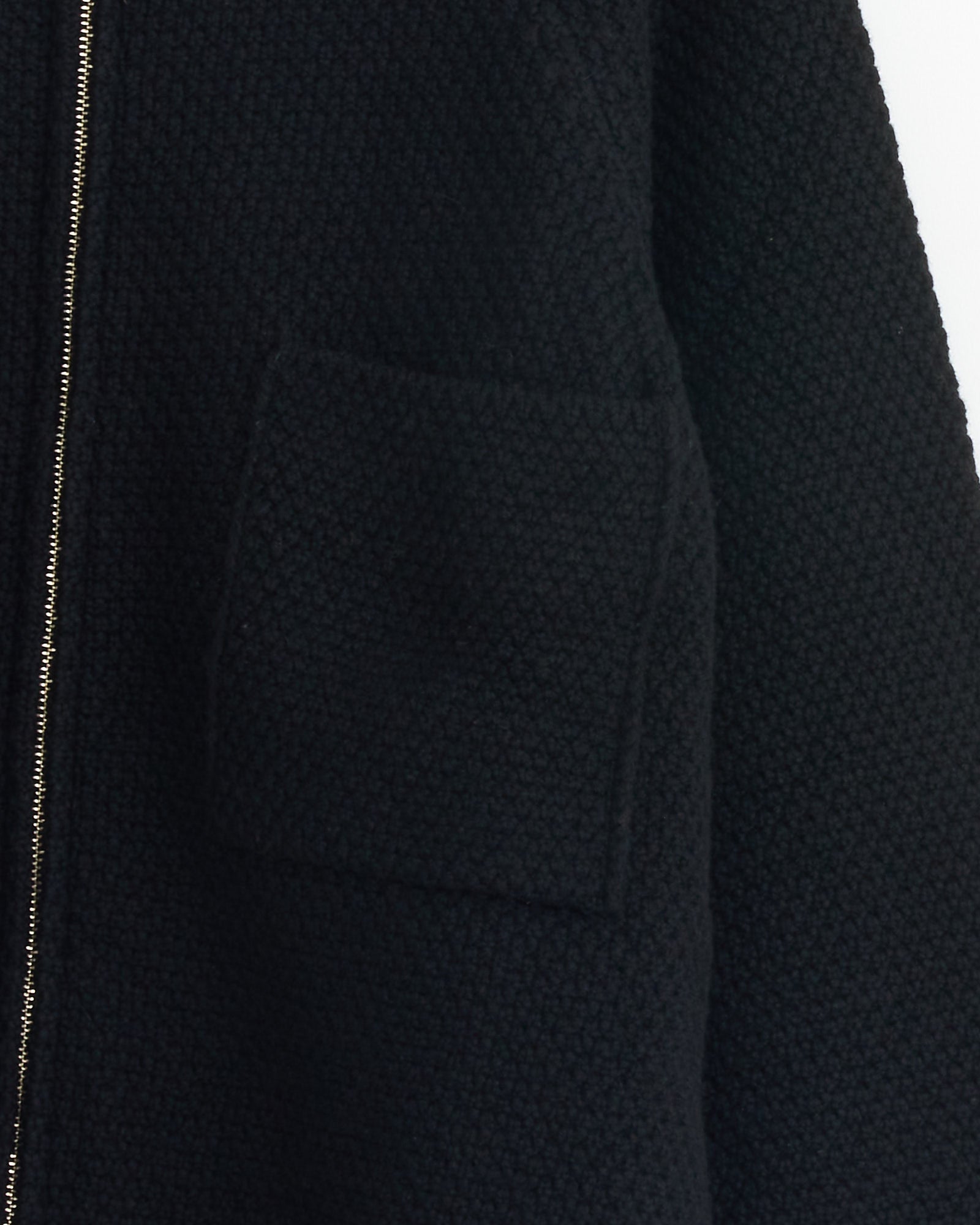 Close-up of Still By Hand's 5G Knitted Blouson in Black, crafted in Japan from textured merino wool, with a visible patch pocket and a partially visible silver zipper on the left side.