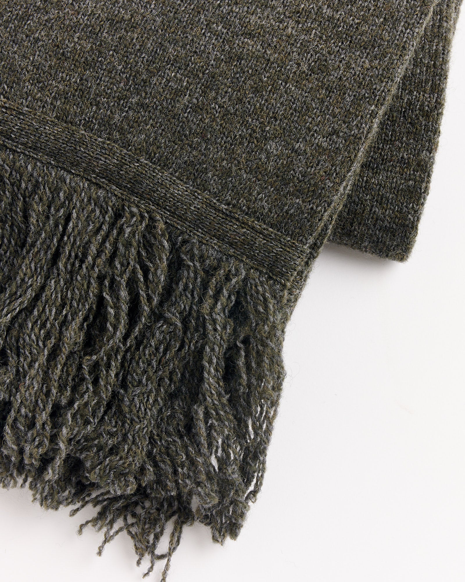 A close-up of the Still By Hand 7G Fringe Muffler in Melange Khaki, a folded woolen scarf with thick twisted fringe, displayed on a white background.