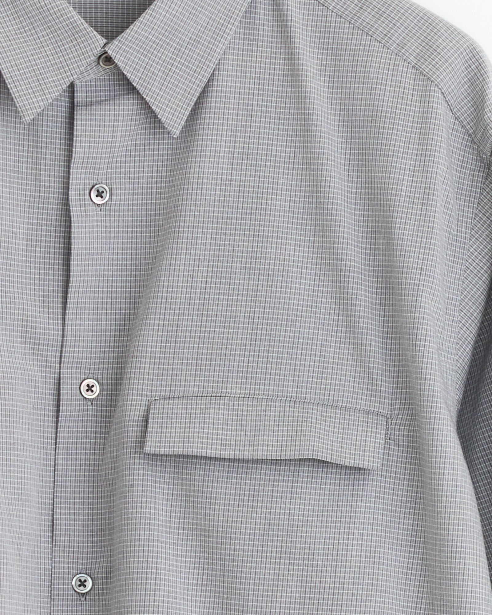 The Still By Hand Oversized Shirt in Grey Check features light gray cotton with a subtle check pattern, a pointed collar, and a single buttoned flap chest pocket. Made in Japan.