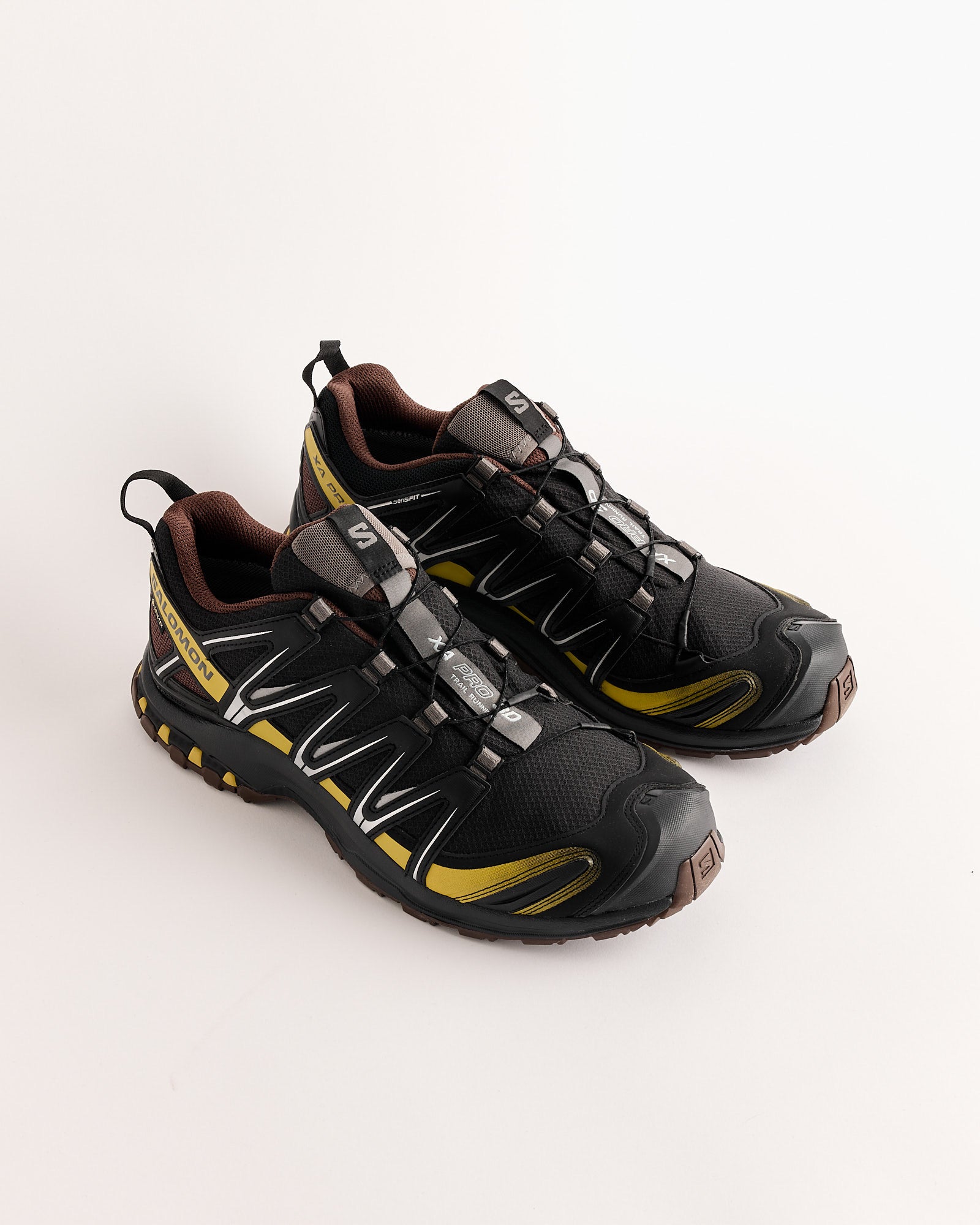 A pair of Salomon XA PRO 3D GTX Sneakers in Black/Crgree/Roast with sturdy soles, mesh uppers, and quick-lace systems, shown side by side on a white background.