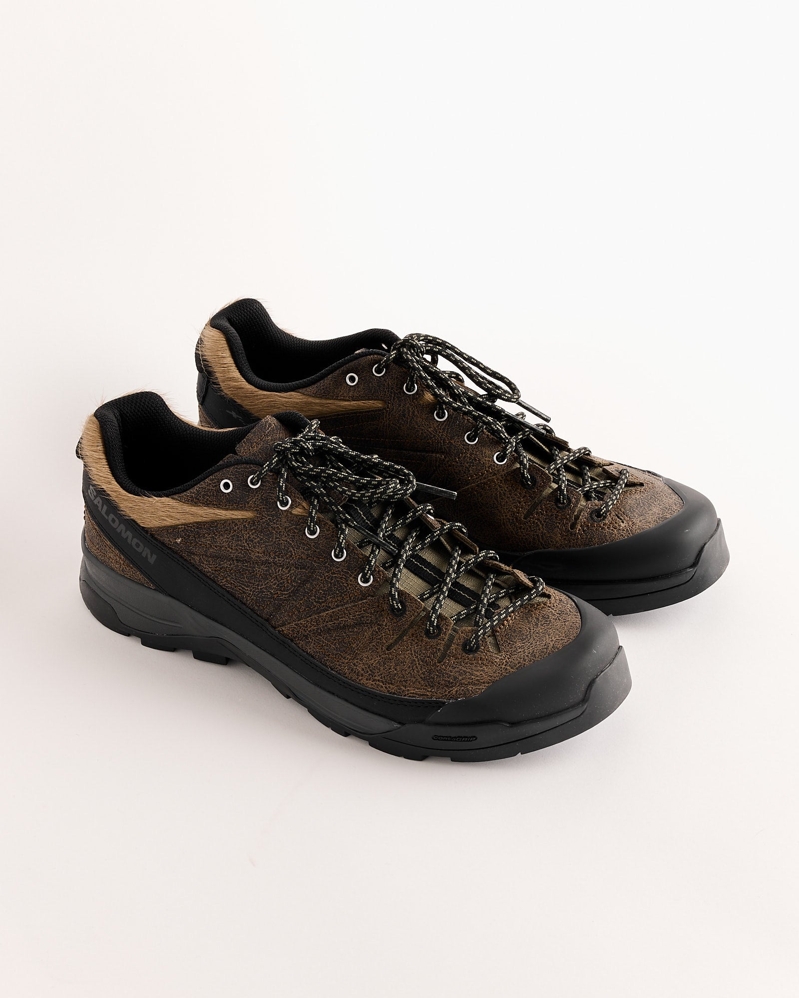 The Salomon X-ALP LOW DISTRESSED LEATHER shoes in Dkeart/Black feature rugged soles, black laces, and distressed leather, shown against a plain white background.