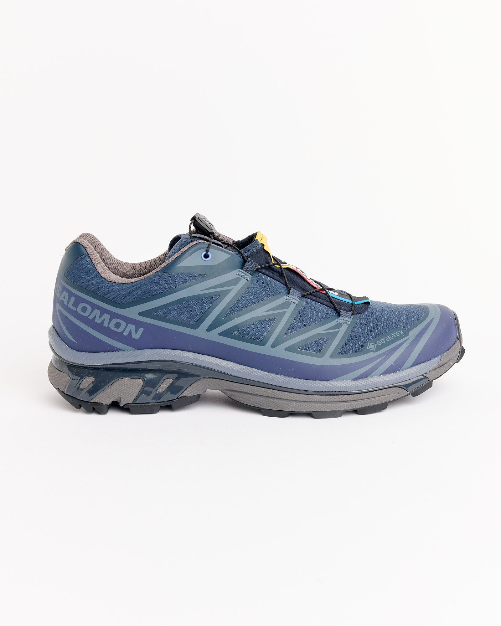 The Salomon XT-6 GTX in Blue Nights/Astral/Pkiten features gray and light blue accents, a black and gray sole, and a quick-lace system, displayed in a side profile on a white background.