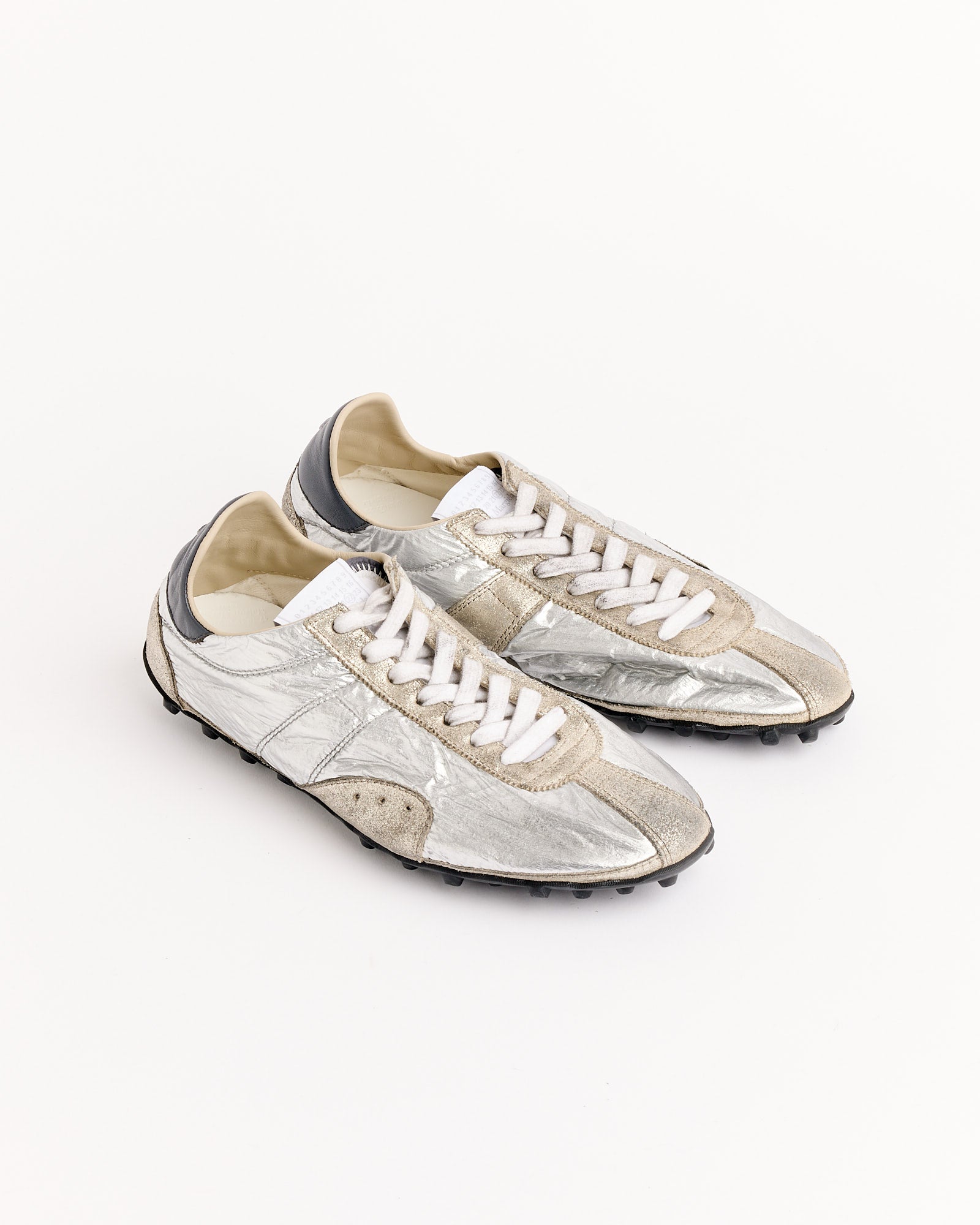 The Maison Margiela Sprinters Low Top in Silver features metallic silver and beige uppers, white laces, and black soles. Displayed on a white background. For sizing or fit questions, contact us via online chat for assistance.