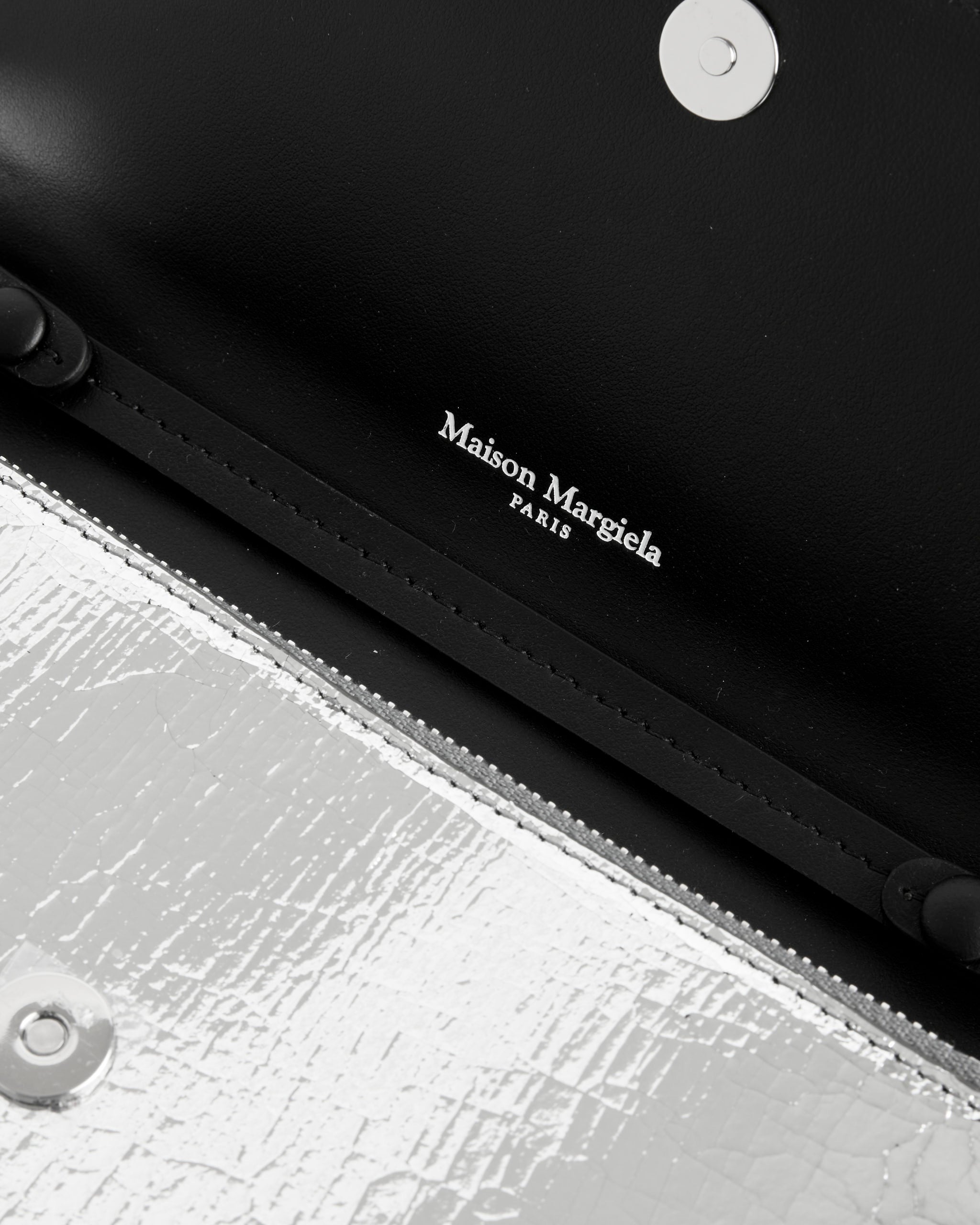 Close-up of the Maison Margiela Broken Mirror Chain Wallet, featuring a textured silver exterior, black leather interior, metallic snap closure, and printed brand logo inside.