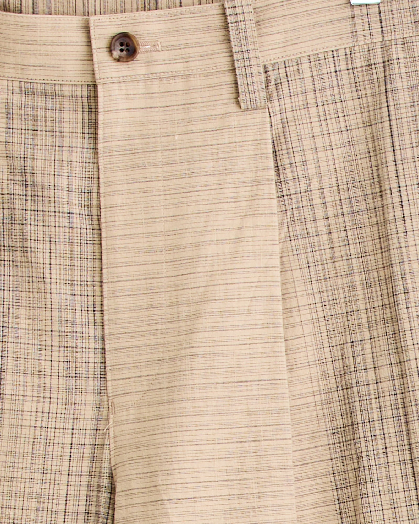 Close-up of the IM MEN Kasuri Pant in Beige, featuring a subtle plaid pattern, button closure, waistband, and part of the fly. The fabric is slightly textured and offers a tailored fit.