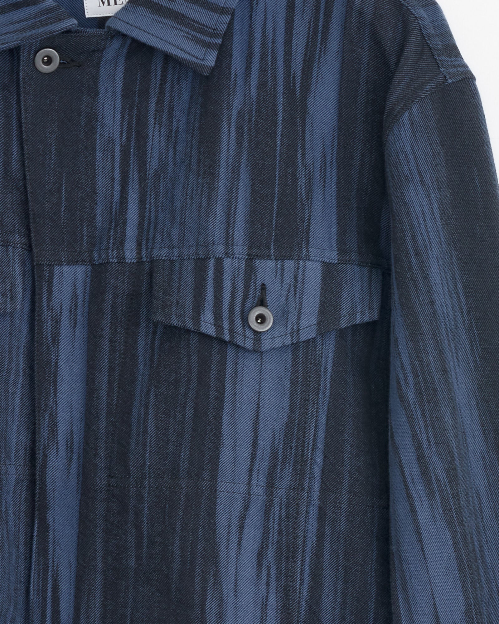 Close-up of the IM MEN Cotton Jacquard Jacket in Dark Blue, showcasing a streaked blue and black pattern, front buttoned flap pocket, and a partially visible collar. Made in Japan for outstanding quality and style.