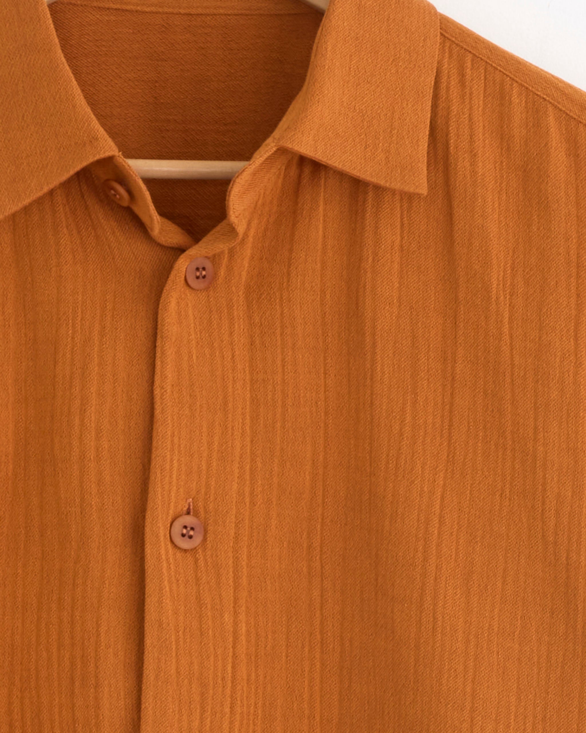 Close-up of the IM MEN Double Weave Crepe Shirt in Dark Orange on a wooden hanger, highlighting the collar, buttons, and upper details—ideal for assessing sizing or discussing fit online.