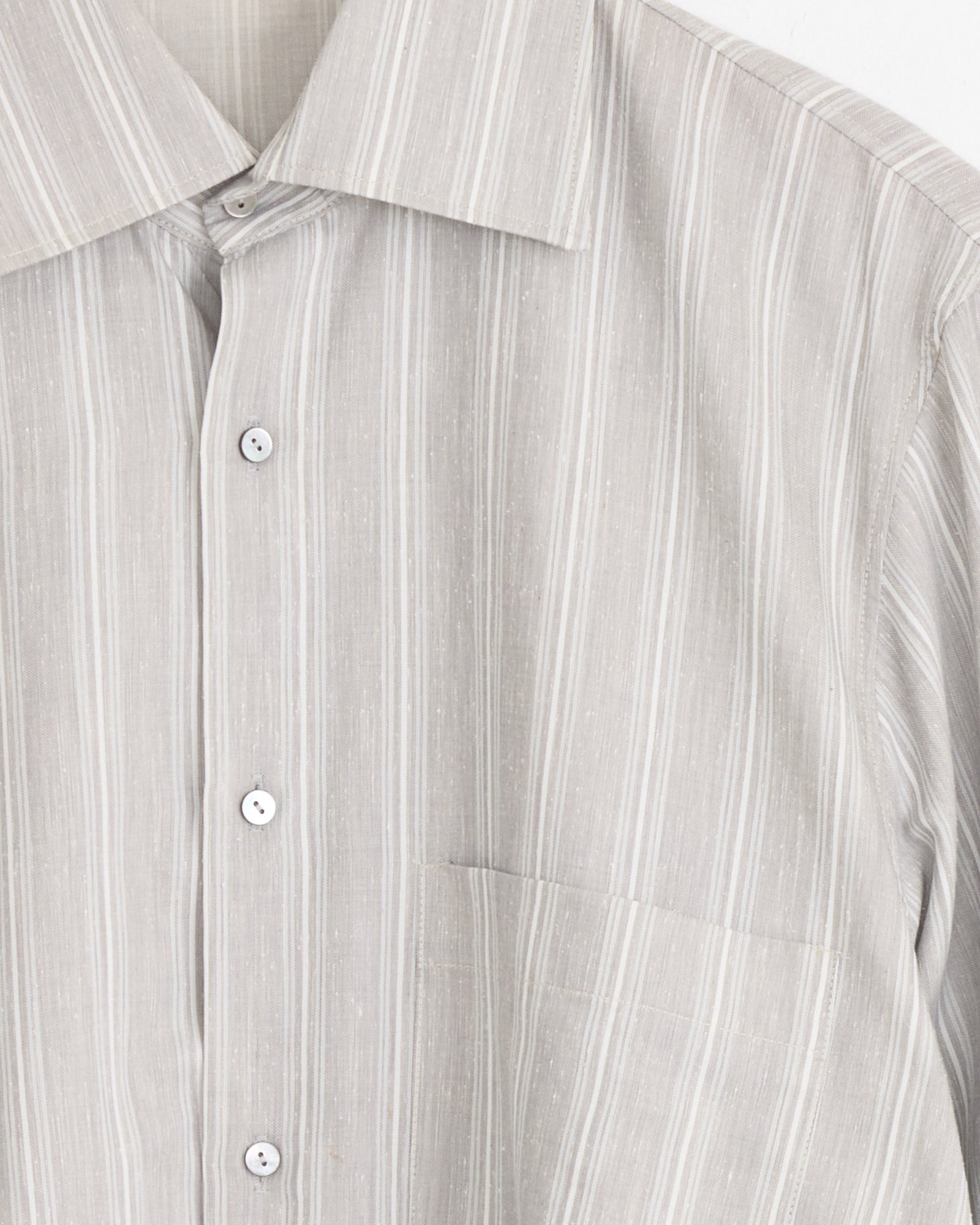 A close-up of the Stoffa Spread Collar Shirt in Steel Grey/Pearl Stripe, made in Italy, featuring thin white vertical stripes, a left chest pocket, pointed collar, and four visible buttons.