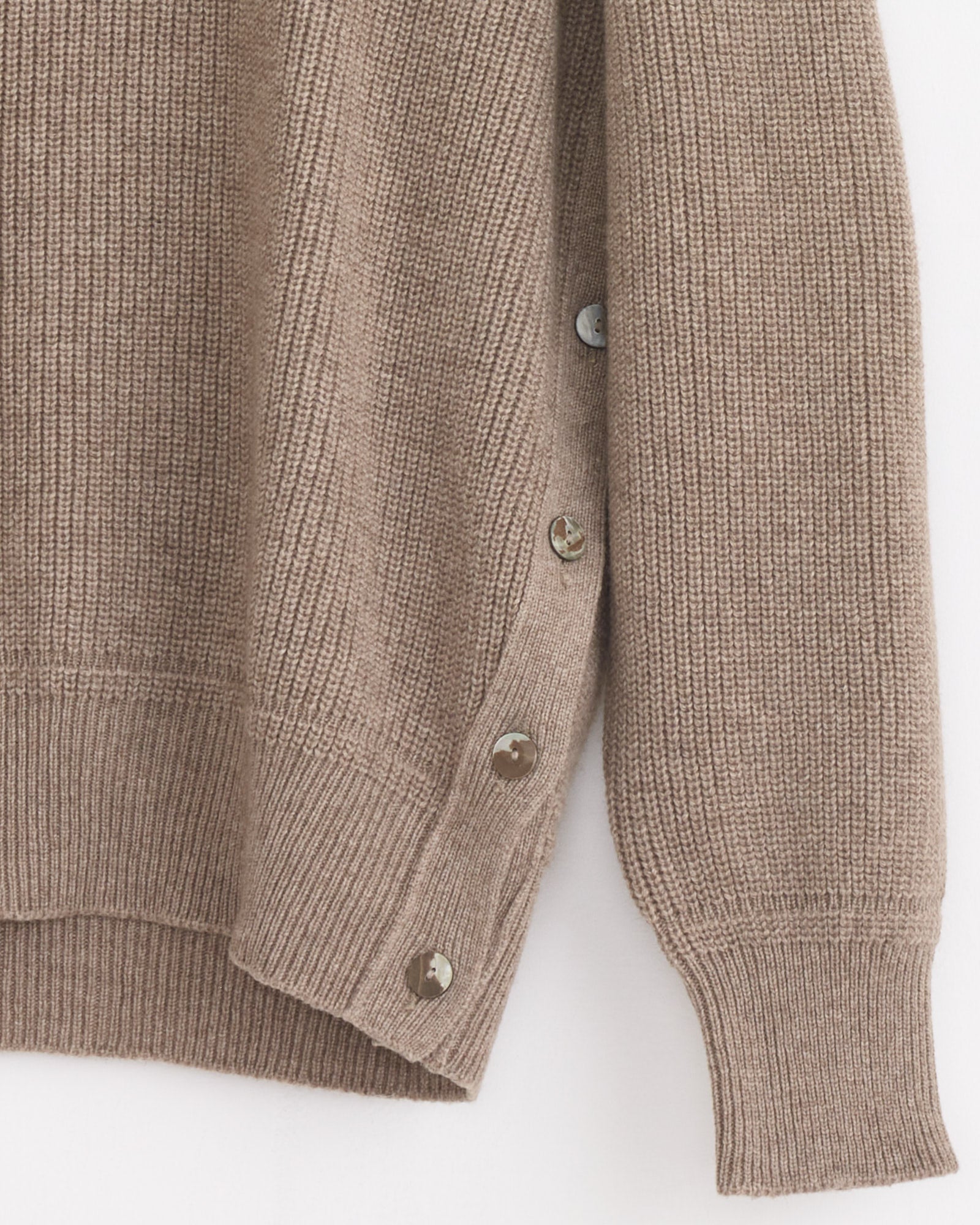 A close-up of the Stoffa Side Button Crewneck in Undyed Taupe, an Italian-made cashmere sweater with ribbed cuffs and hem, featuring a row of five shiny side buttons for both decoration and function.