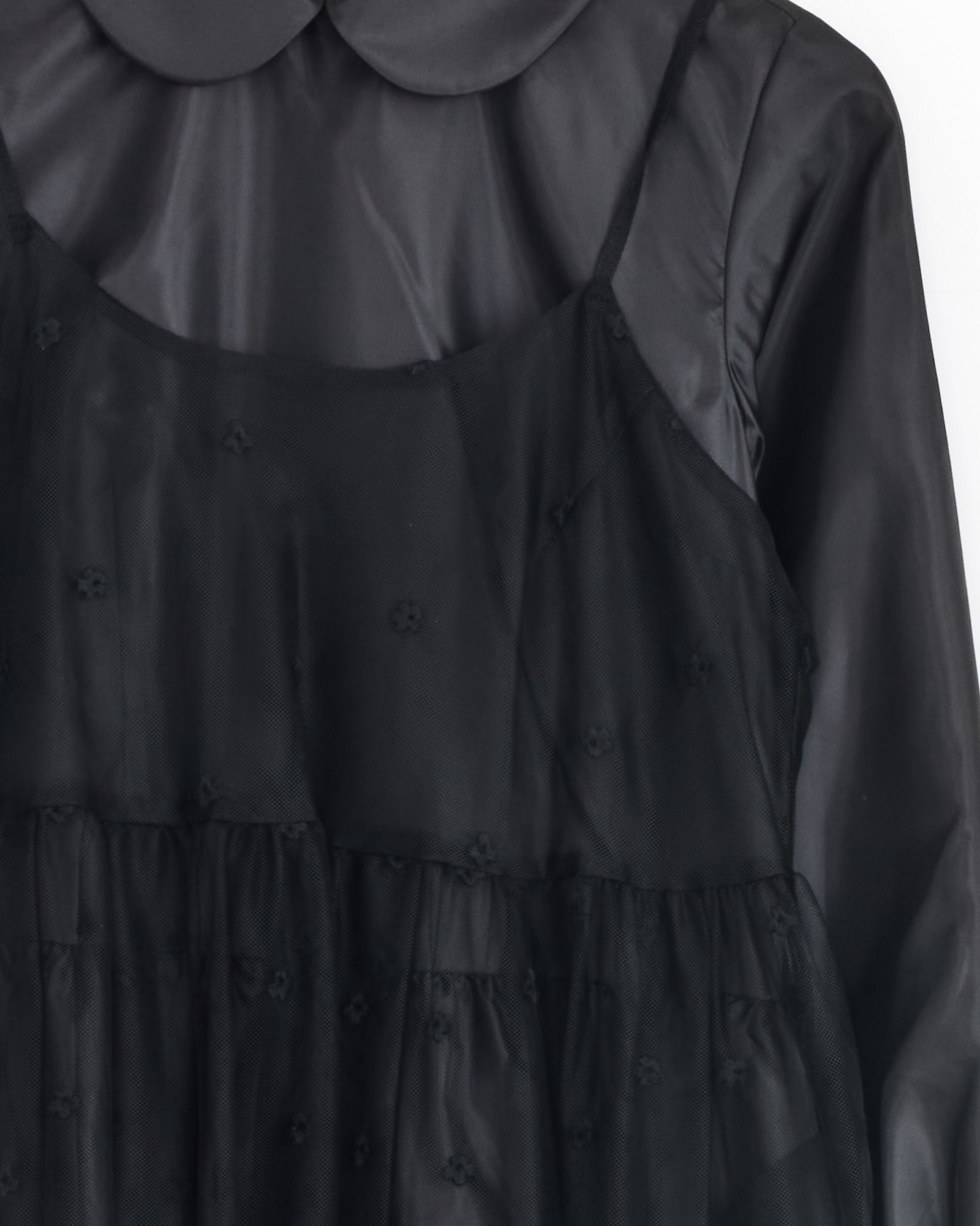 Close-up of the Comme Des Garçons Girl Tulle Embroidered Overlay Dress in Black, featuring a Peter Pan collar, long sleeves, and delicate floral embroidery layered over sheer tulle fabric.