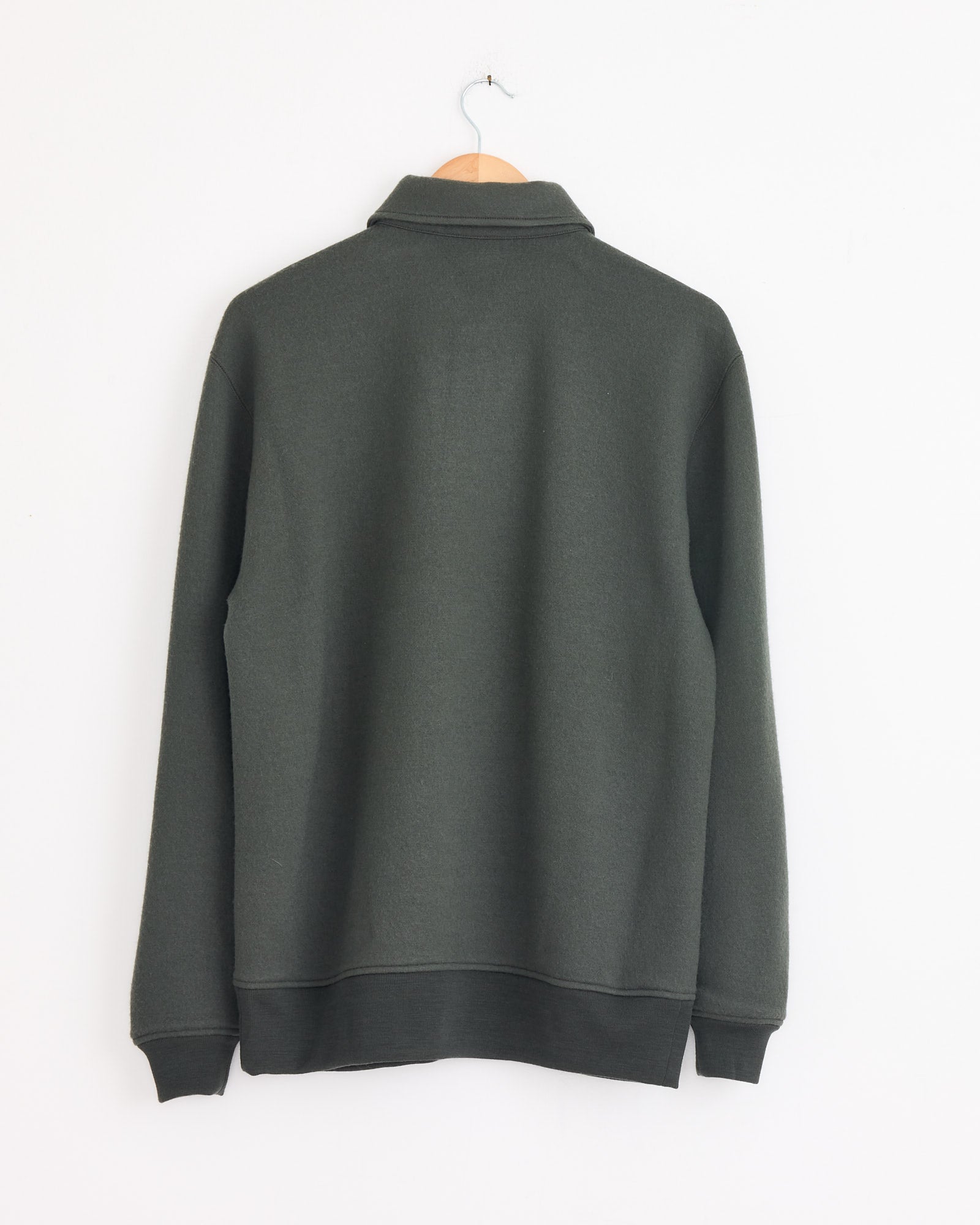 The Cale 120 Air Wool Fleece Polo in Khaki, shown from the back on a wooden hanger against a white wall, features long sleeves and is made in Japan for exceptional quality and comfort.