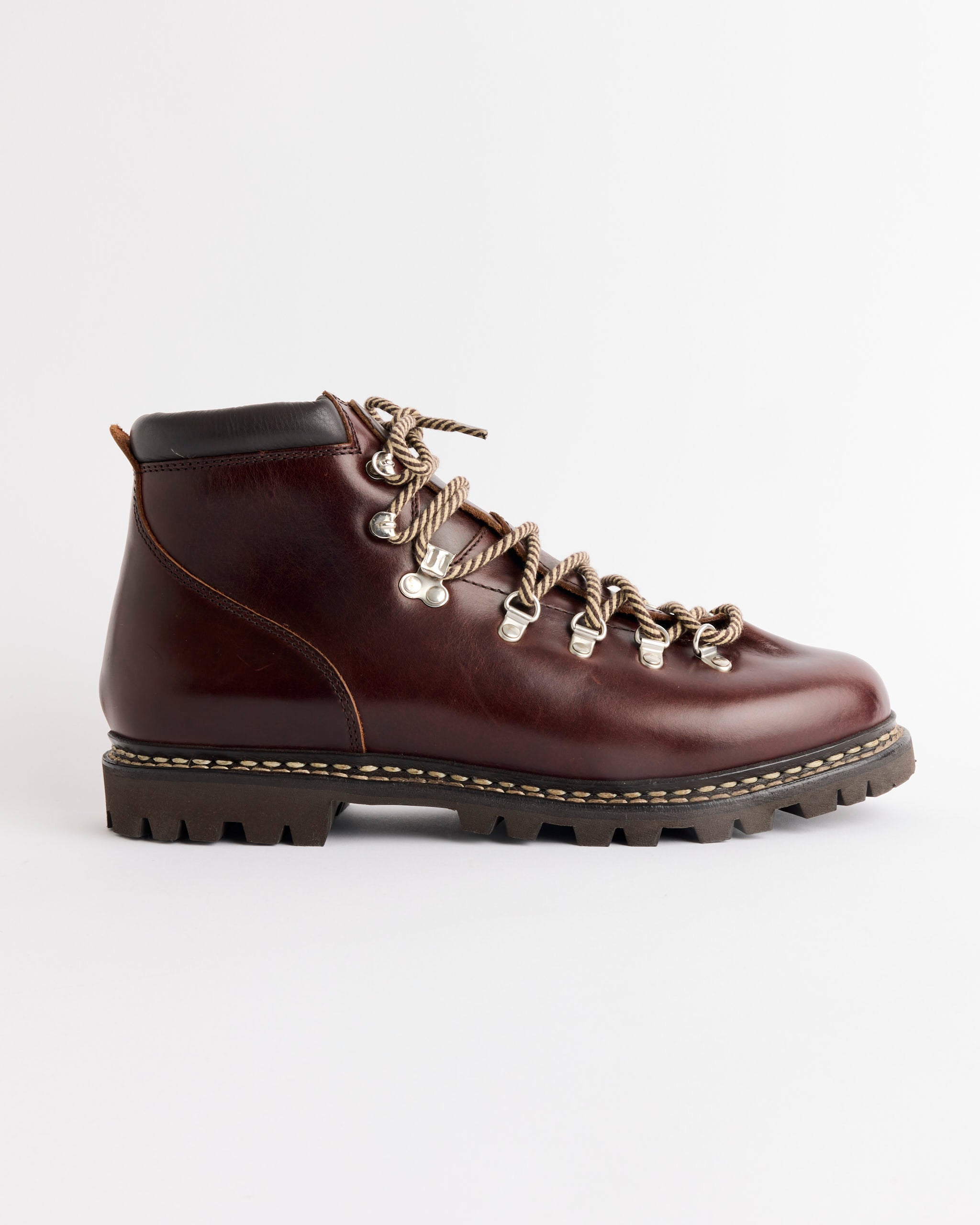 The Paraboot Avoriaz in Lisse Ecorce is a brown leather hiking boot with Norwegian welted construction, black padded collar, thick lug sole, and striped laces, shown in profile on a white background and handmade in France.