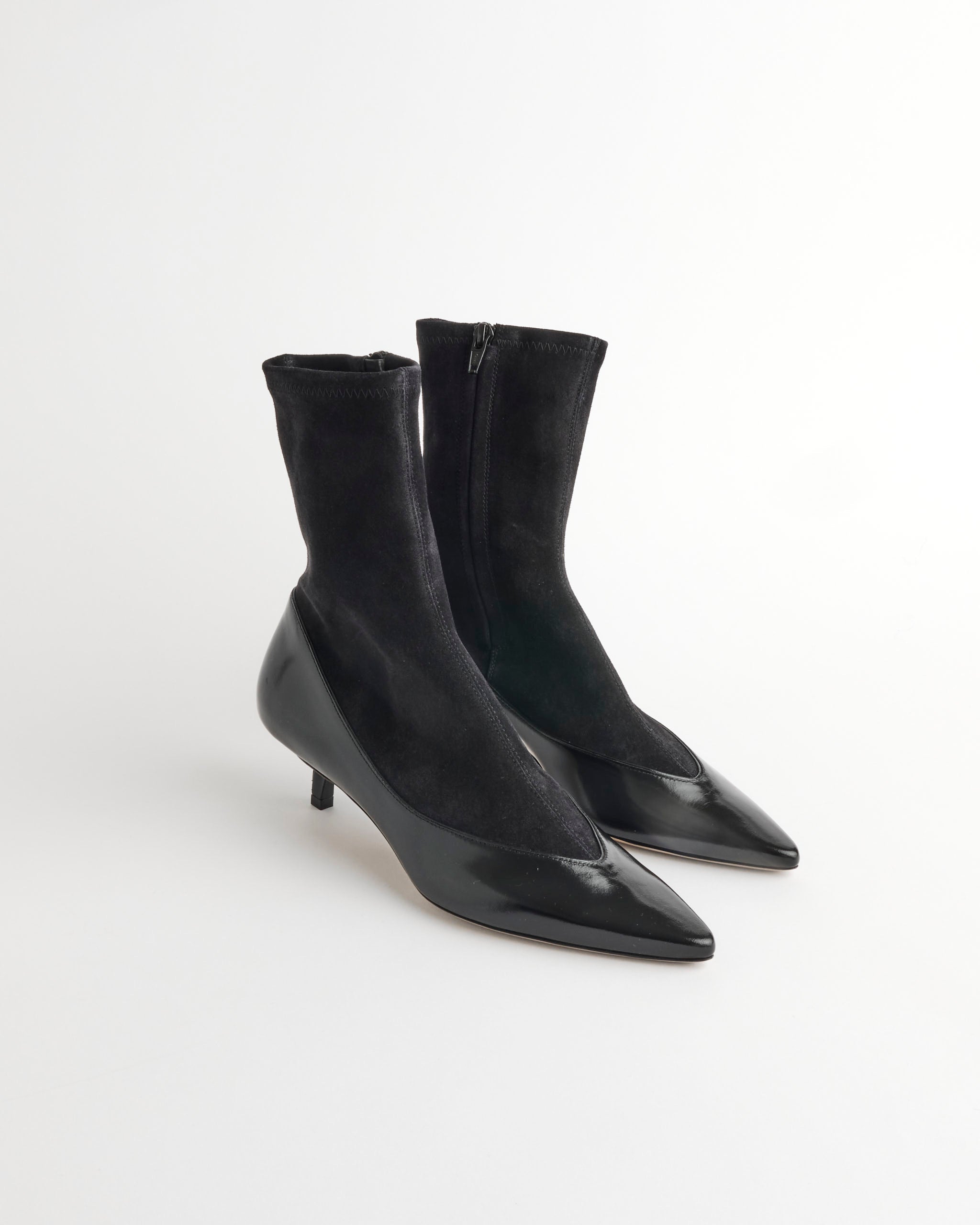 The Jacquemus Les Bottines Tourni Pump Boot in Black features pointed toes, a glossy lower, matte stretch suede shaft, side zipper, and short kitten heels, shown on a plain white background.