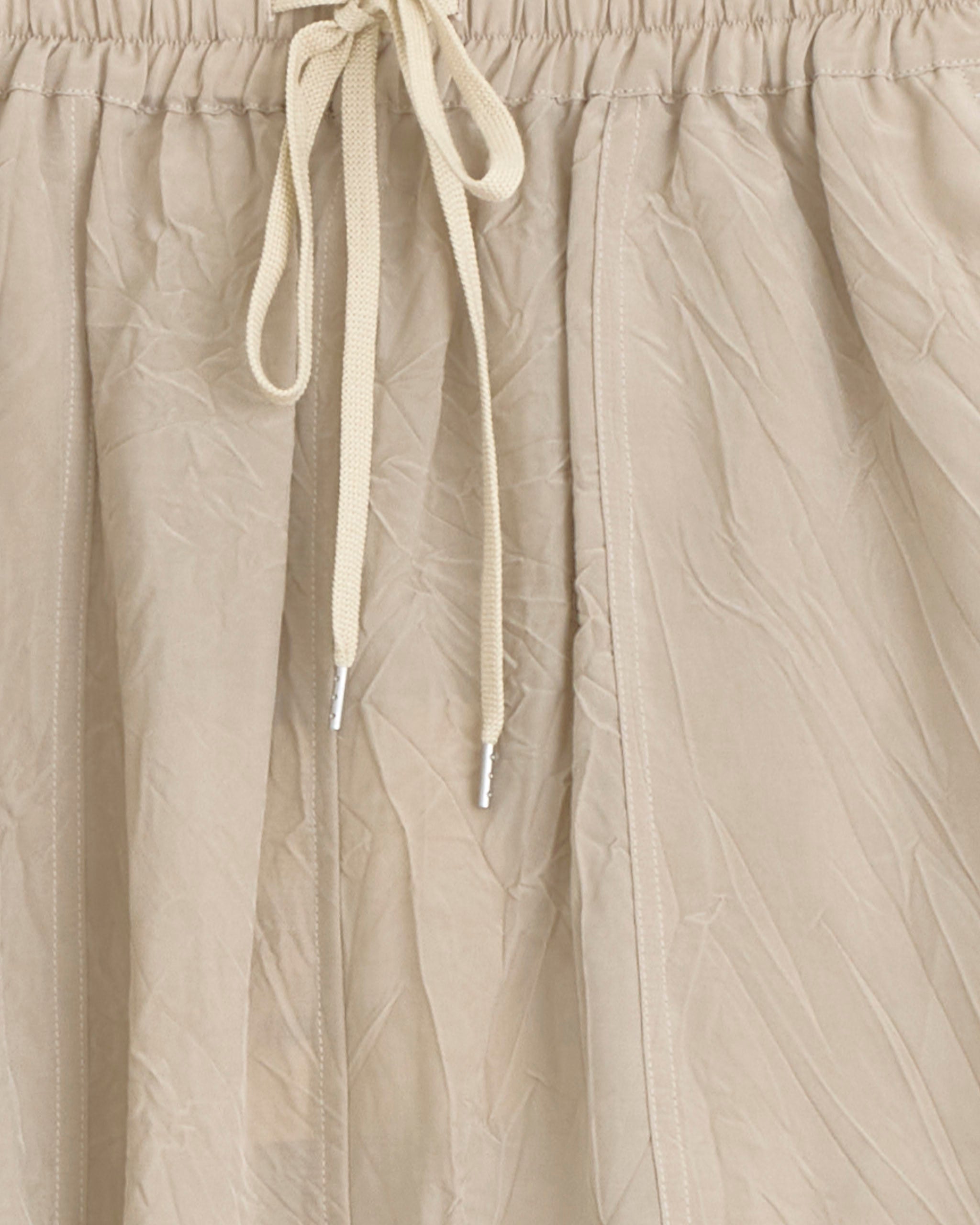 Close-up of Studio Nicholson’s Oates Skirt in Sable, crafted from lightweight beige fabric with an elastic waistband and cream drawstring. Features a subtle sheen and Italian patch pockets for a stylish, workwear-inspired look.