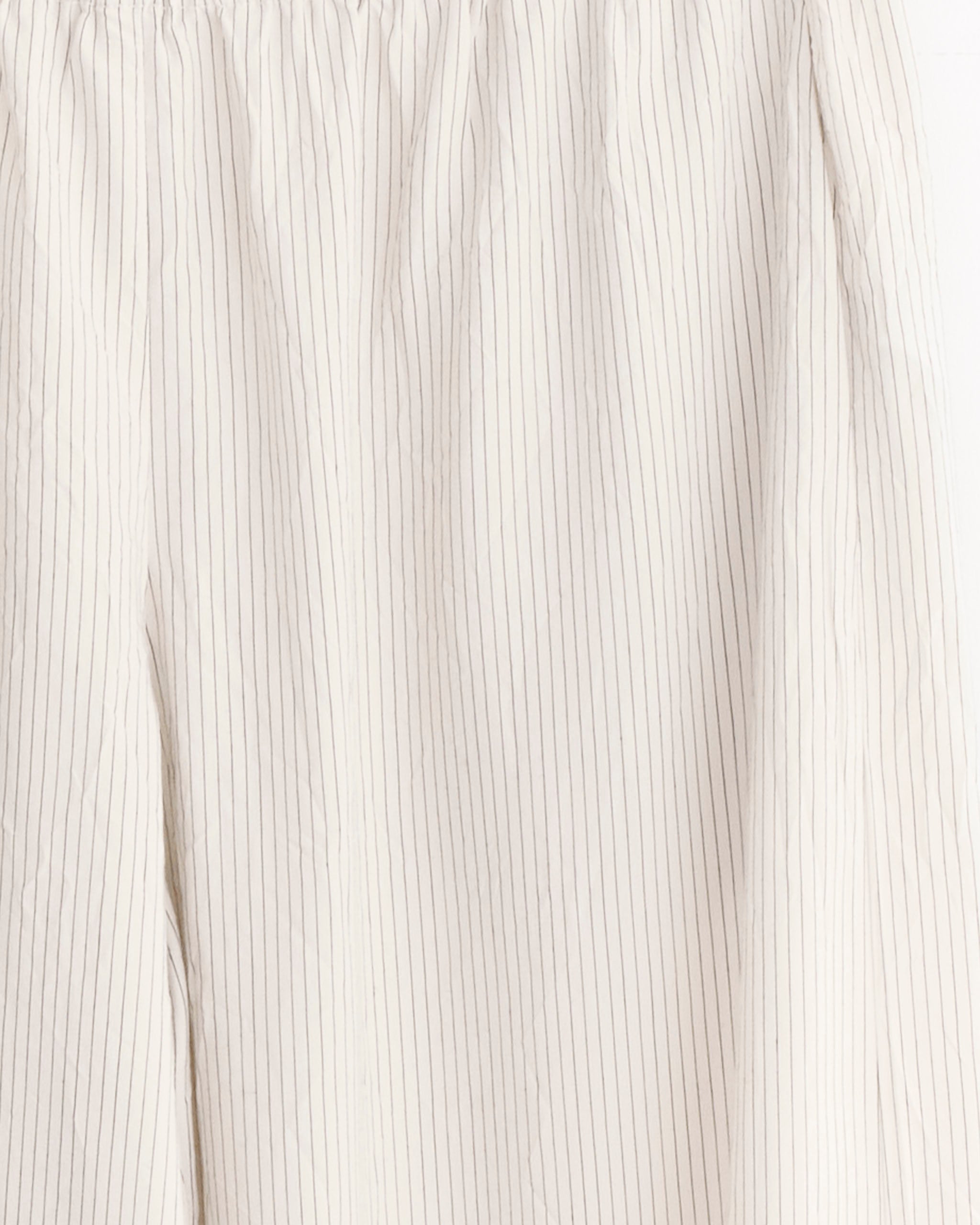 Close-up of a light-colored fabric with thin gray pinstripes, softly wrinkled and likely part of the Relaxed Crushed Pant in Petite Pinstripe by ST. AGNI.