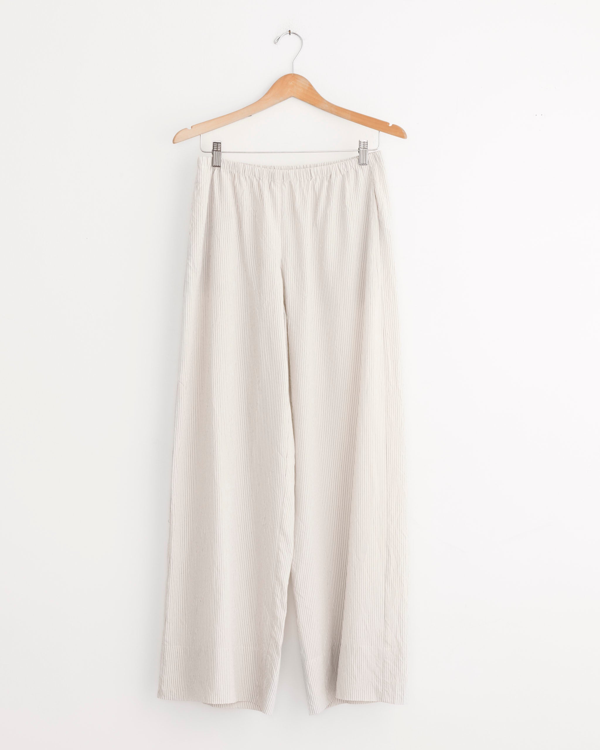 ST. AGNI Relaxed Crushed Pant in Petite Pinstripe with a mid-rise straight leg and elastic waistband, displayed on a wooden hanger against a plain white background.