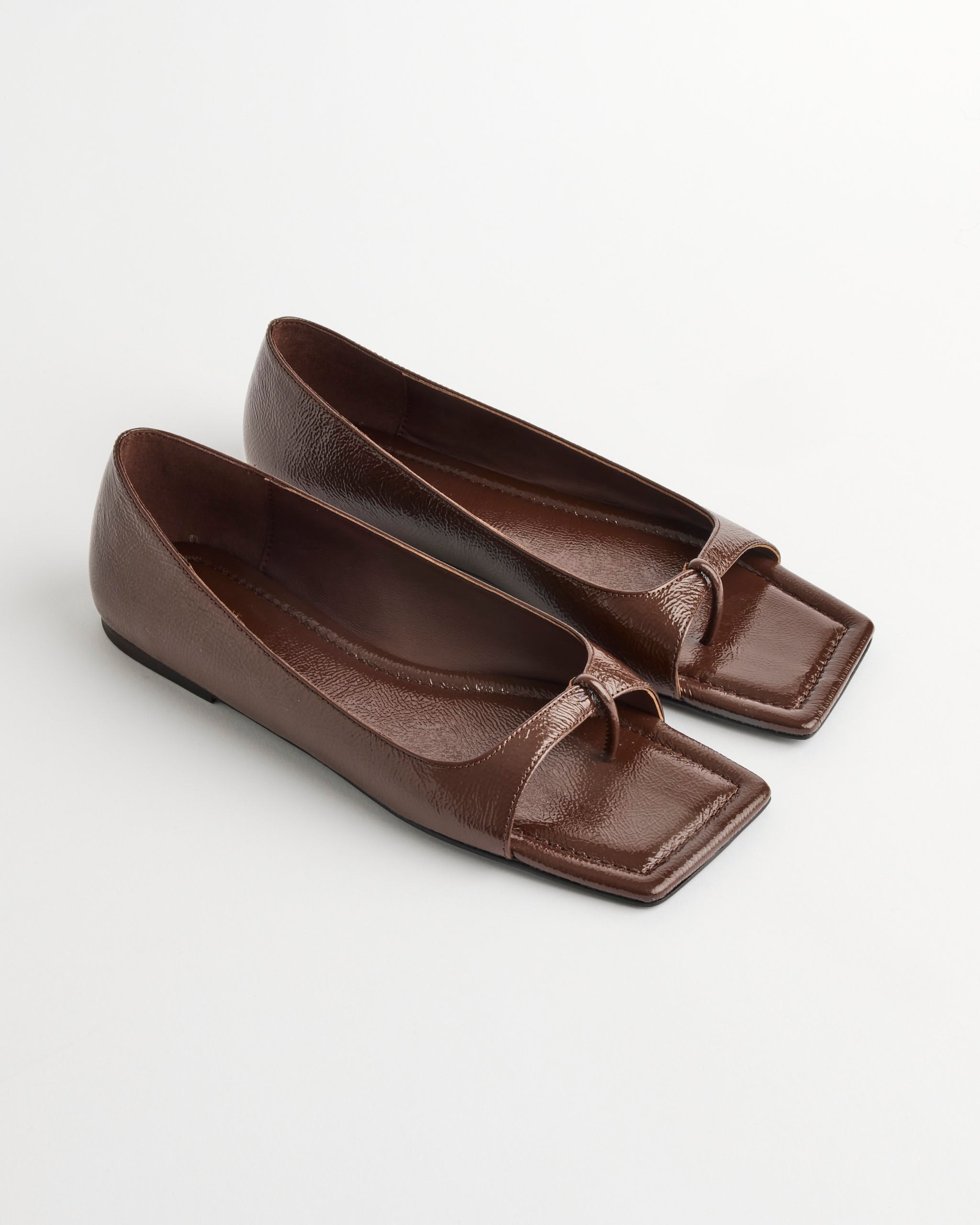 A pair of ST. AGNI 90s Square Toe Flat Shoes in Patent Liqueur, featuring a cutout design on the front, displayed on a white background.