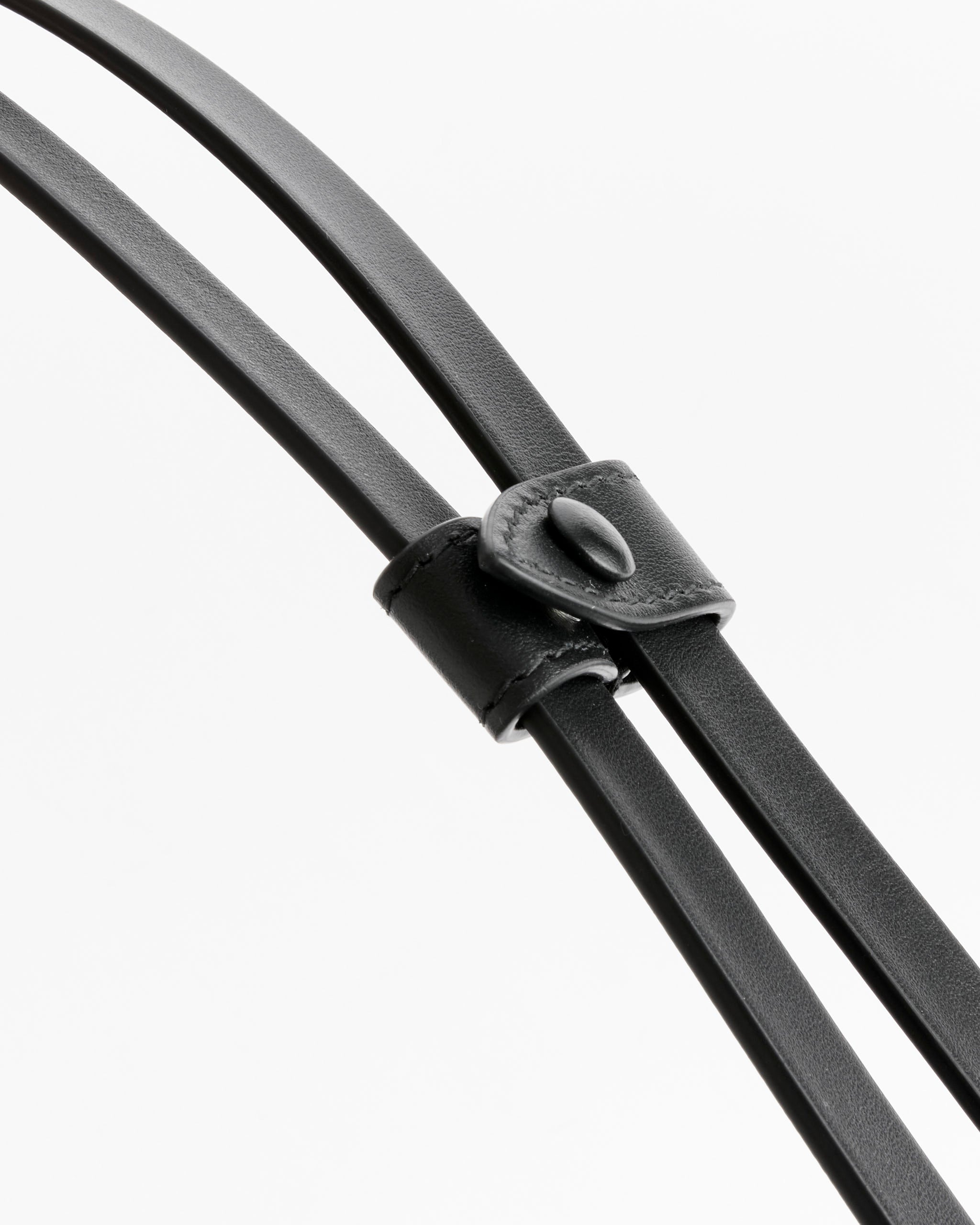 Close-up of two calf leather straps held by a matching loop with button closure, set against white—a signature detail on the Maison Margiela Small Baguette Bag in Black.