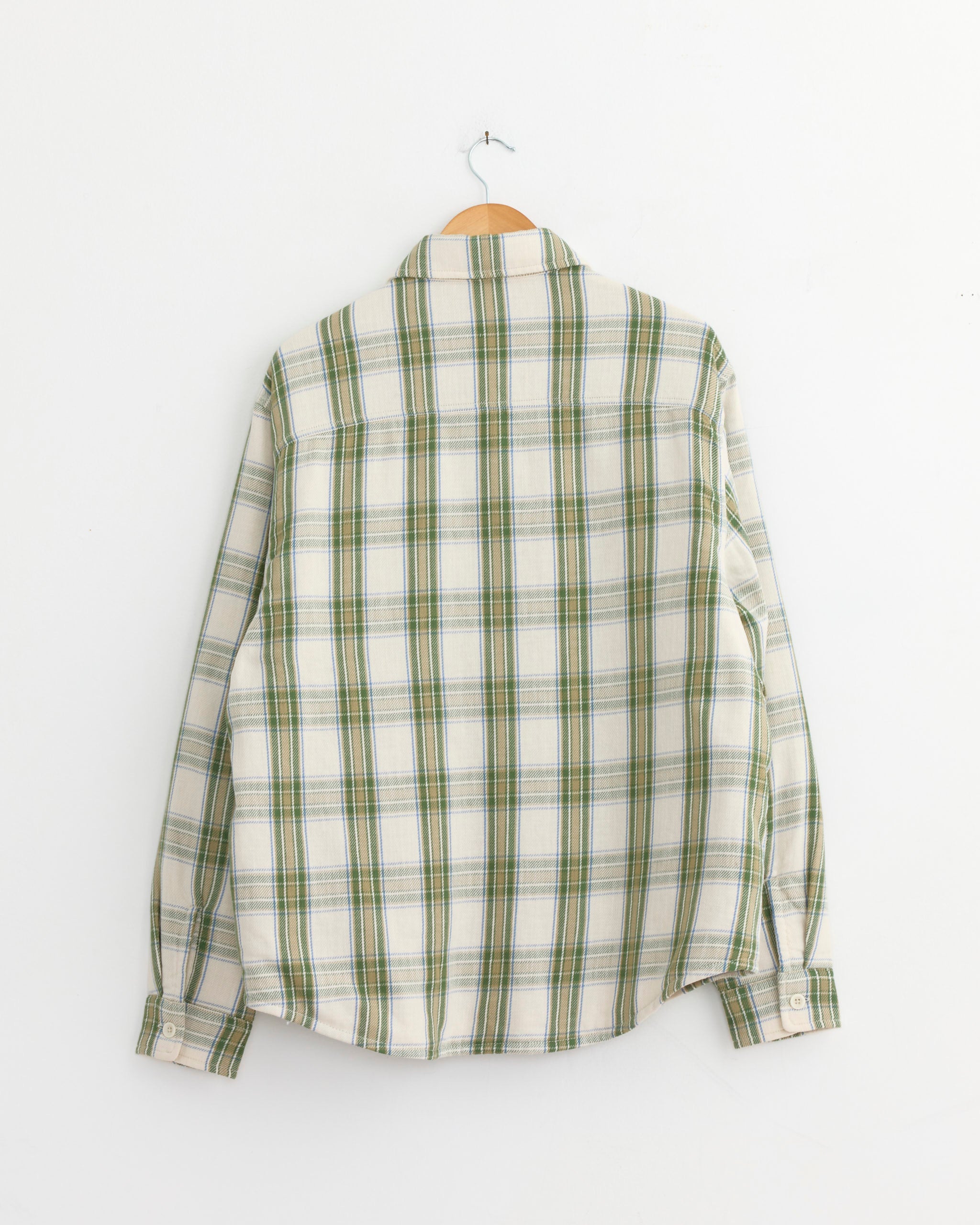 A Stussy Lau Plaid Shirt Jacket in Off White hangs on a wooden hanger against a plain white wall, shown from the back.