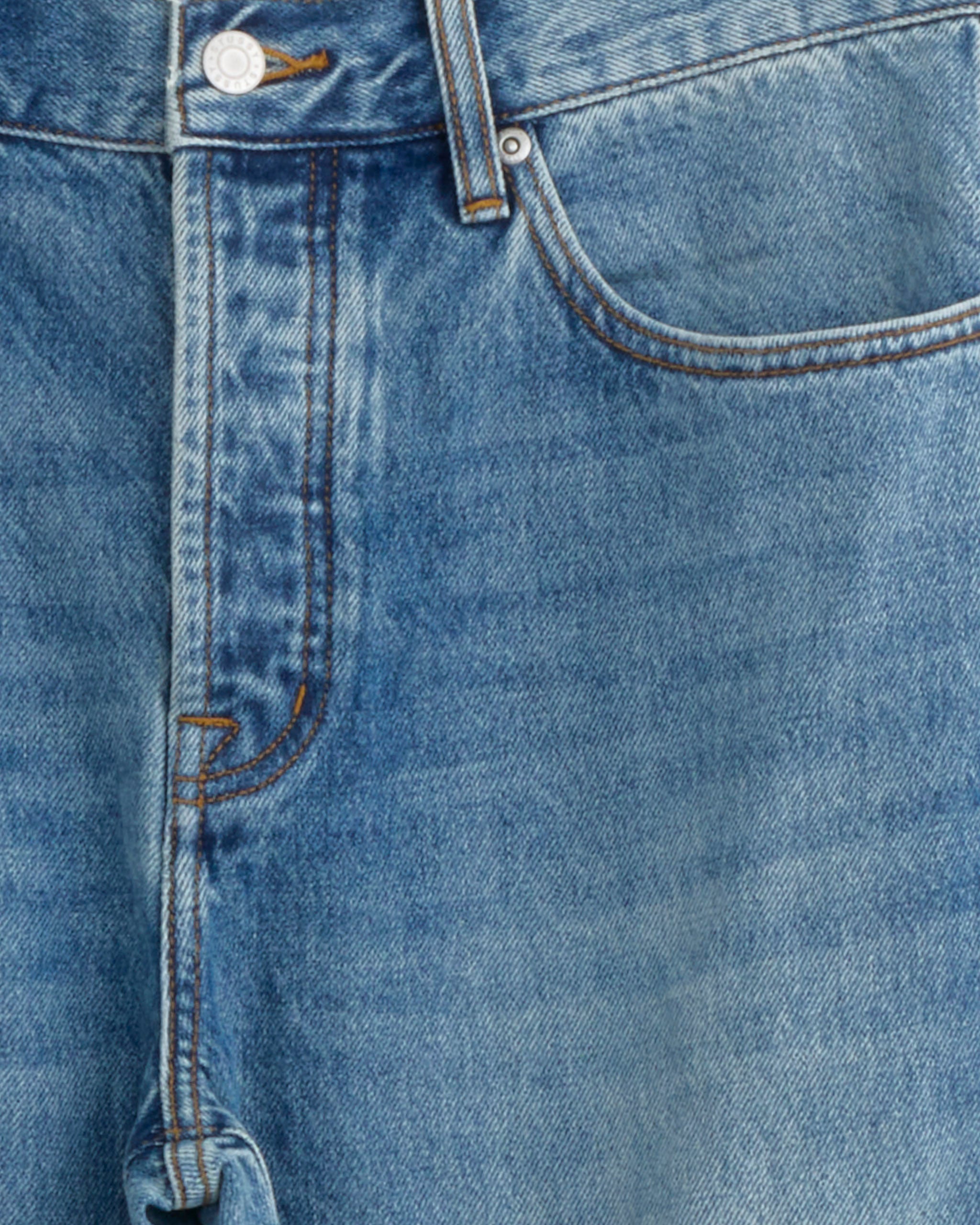 Close-up of Stussy’s New Classic Jean in Indigo Stone Wash, crafted from 100% cotton denim with a front zipper, button closure, and orange-stitched pocket seam.