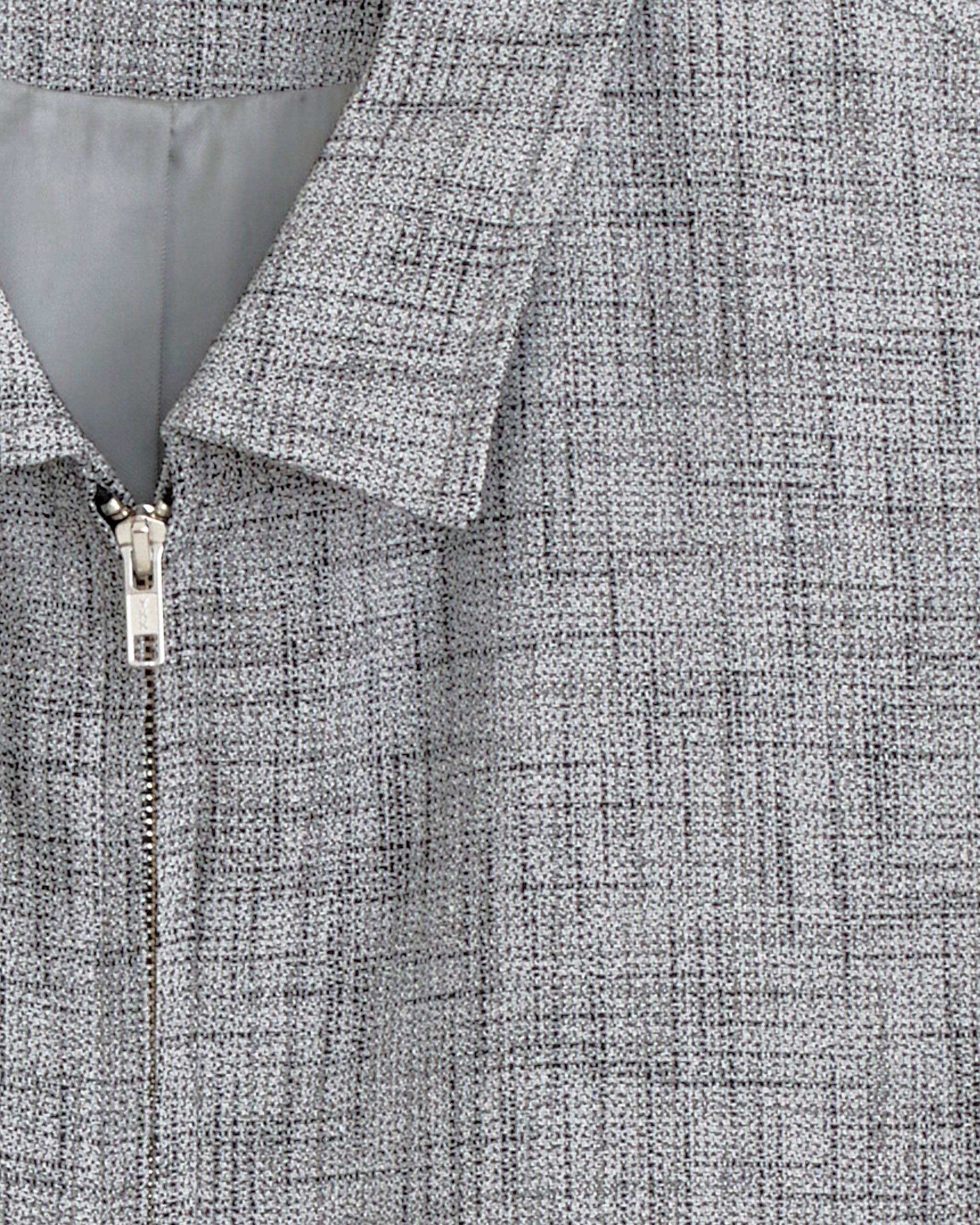 Close-up of the Bode Static Ohio Jacket in Grey, showcasing its textured fabric with a subtle grid, metal zipper, pointed collar, and light gray lining that accentuates the jacket’s refined workwear-inspired silhouette.