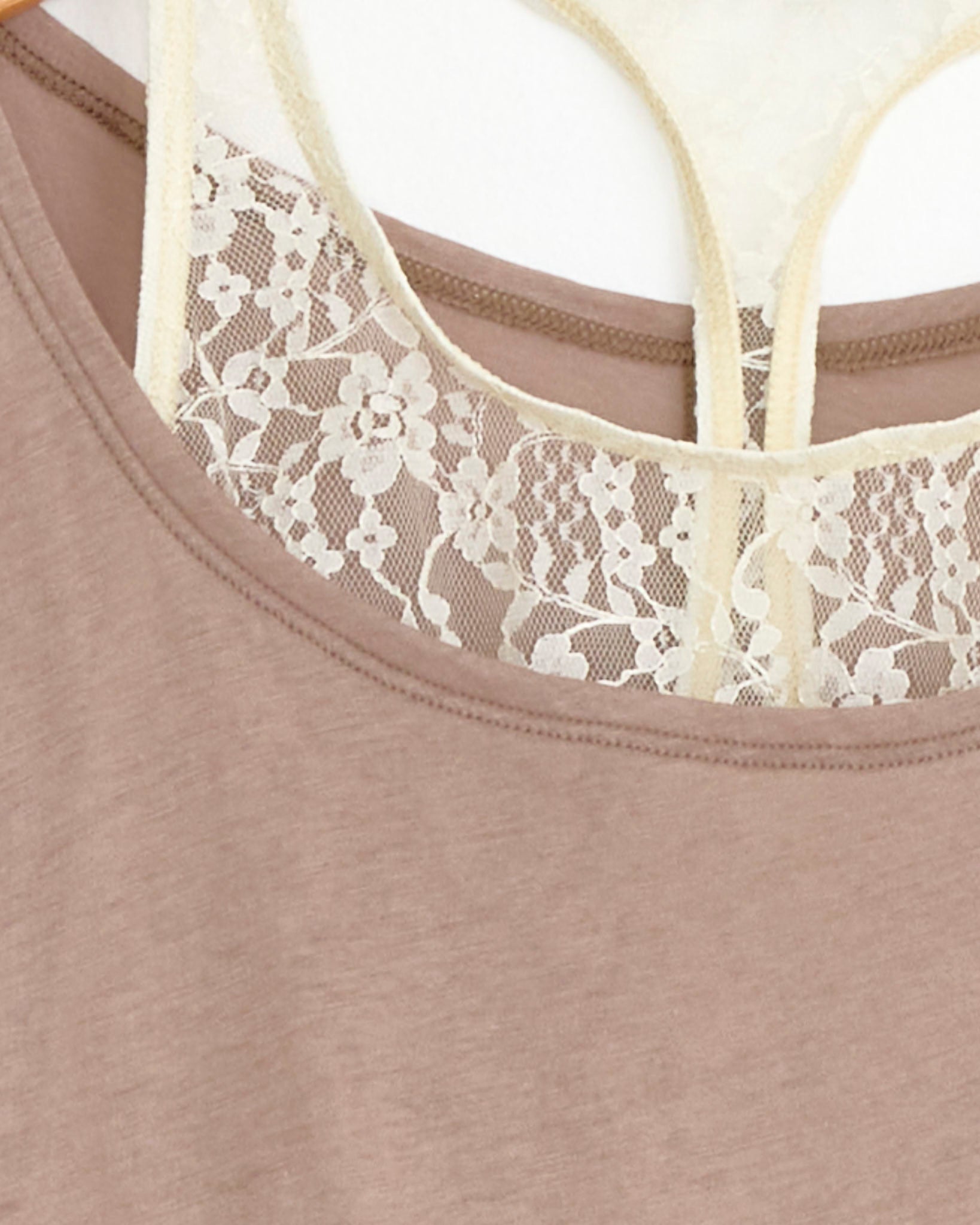 Close-up of Our Legacy's Swim Tank Top in Velvet Sand layered over a cream lace camisole, with delicate lace detailing visible through the neckline and straps.