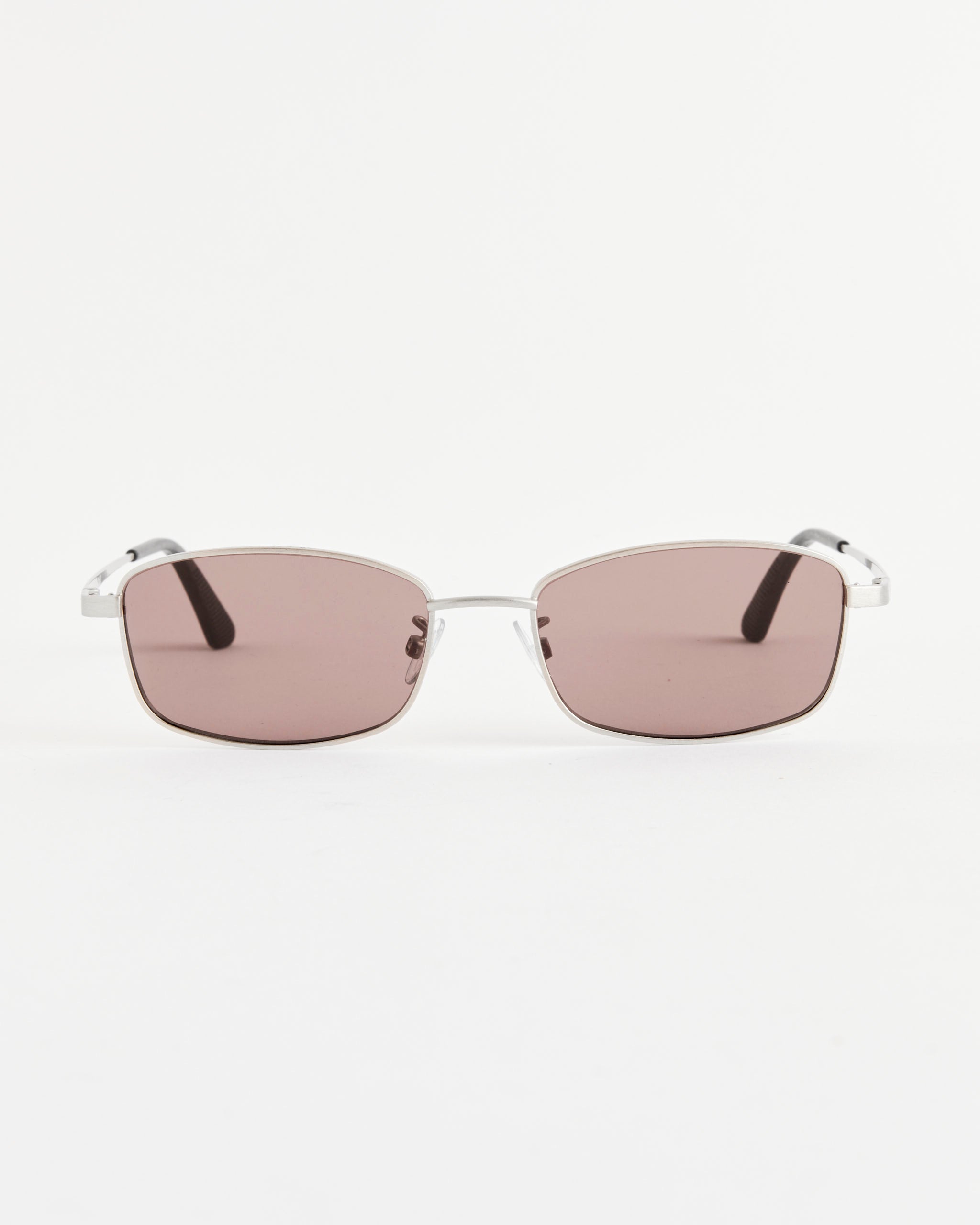 A pair of Our Legacy Librarian Sunglasses in Silver Hawk, featuring a rectangular German silver frame and light pink tinted lenses, displayed against a plain white background.