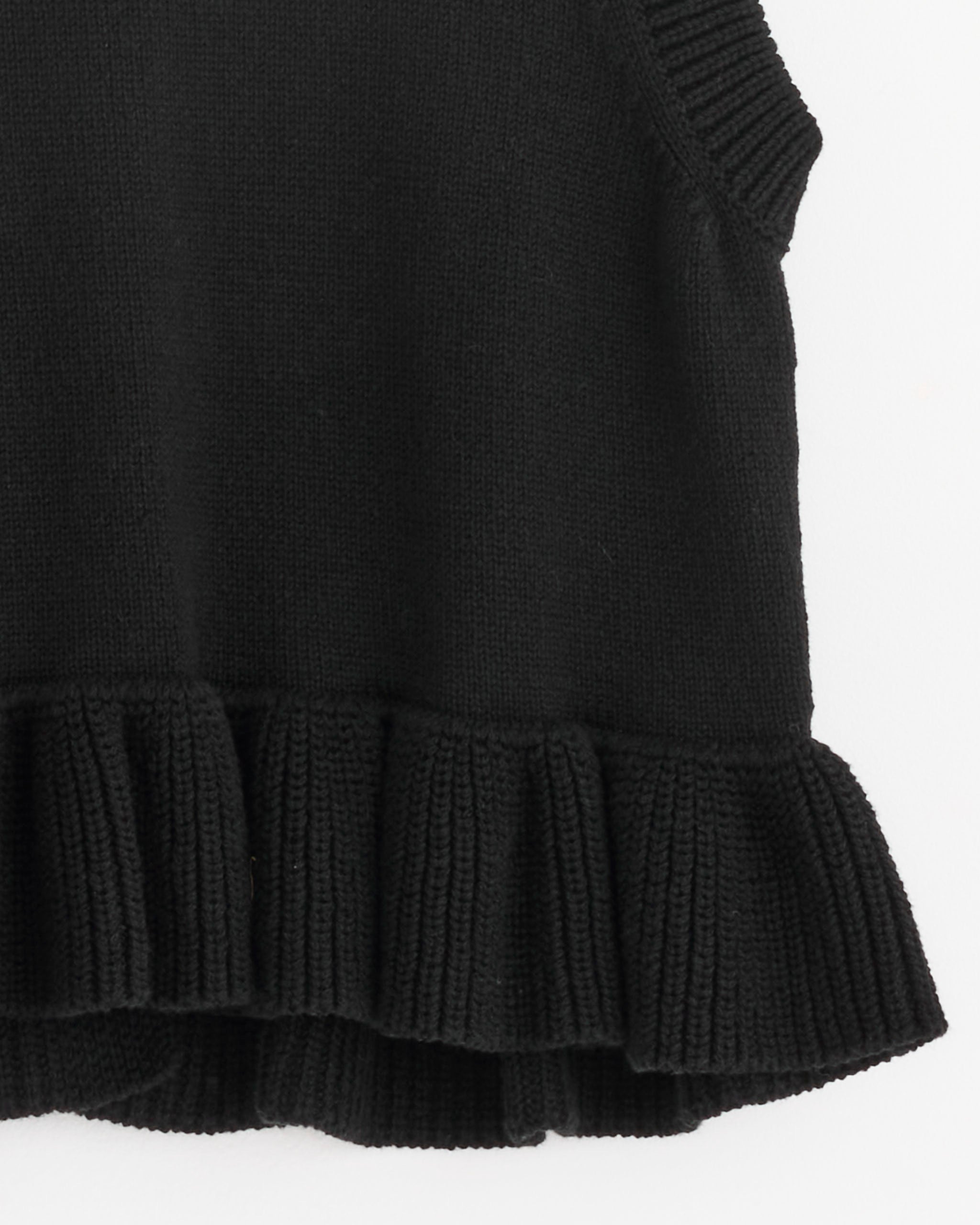 A close-up of the Billie Vest in Black by Cecilie Bahnsen, a sleeveless knit sweater made from recycled cashmere with ribbed ruffle detailing at the hem, set against a white background.
