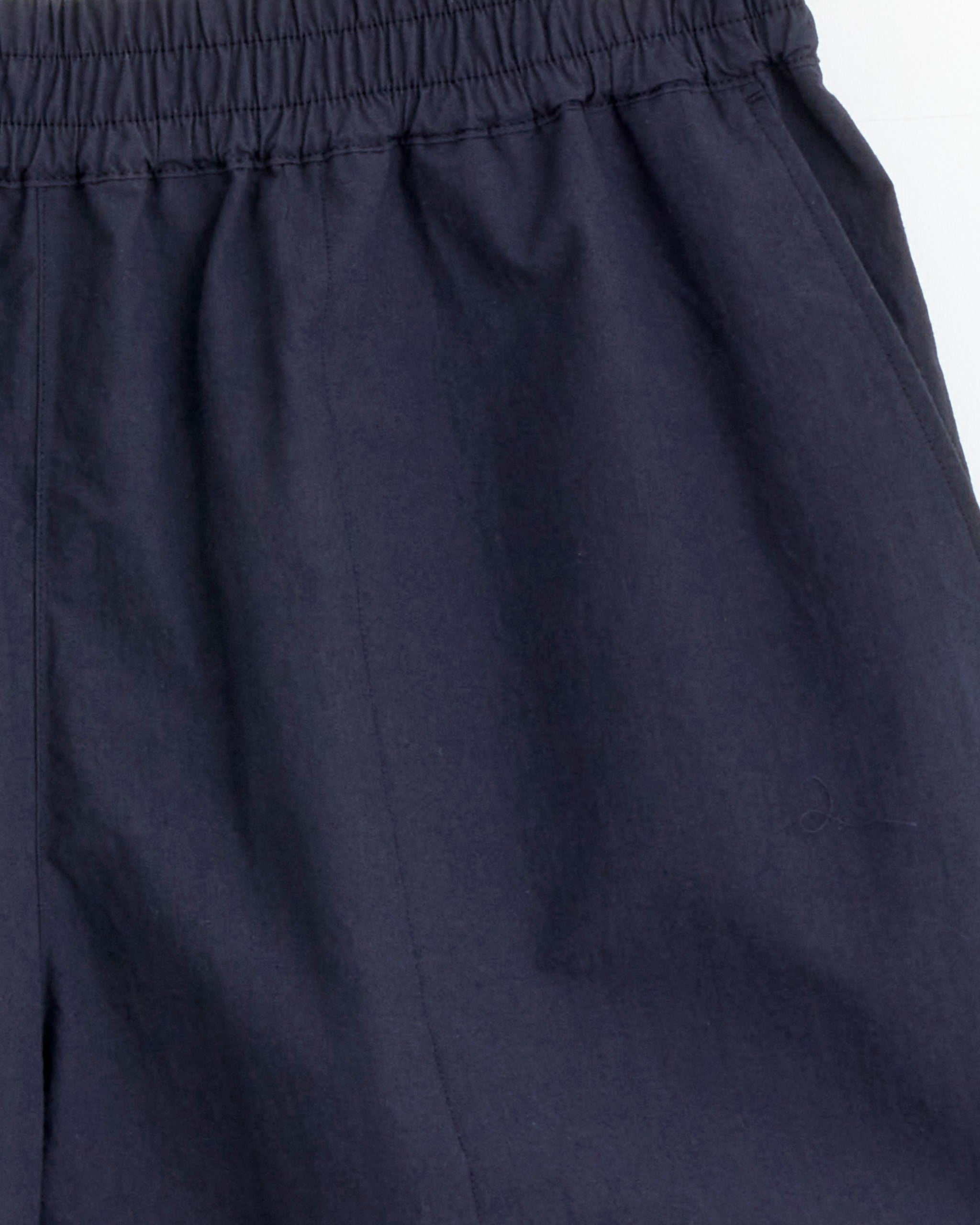 Close-up of the upper section of Studio Nicholson’s Elio Short in Ink, made from typewriter cotton with an elastic waistband and side pocket, shown against a plain white background.