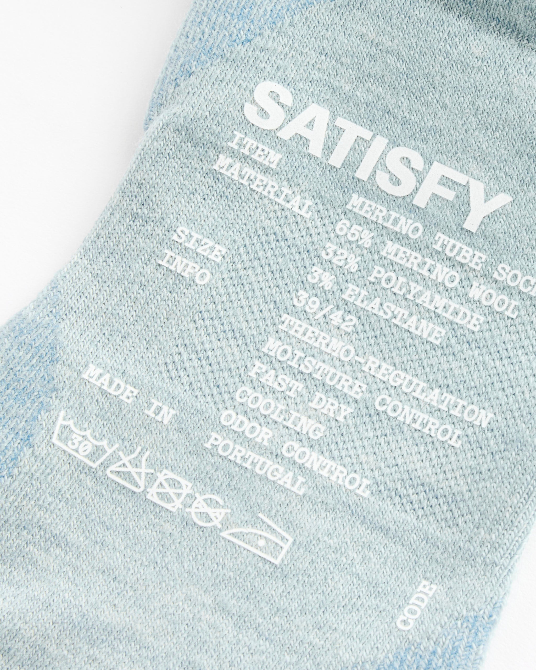 Close-up of Satisfy Running Merino Nylon Tube Socks in Dusty Blue, featuring size, 62% merino wool/34% polyamide/4% elastane material, moisture control info, and manufacturing details—perfect as merino wool running socks.