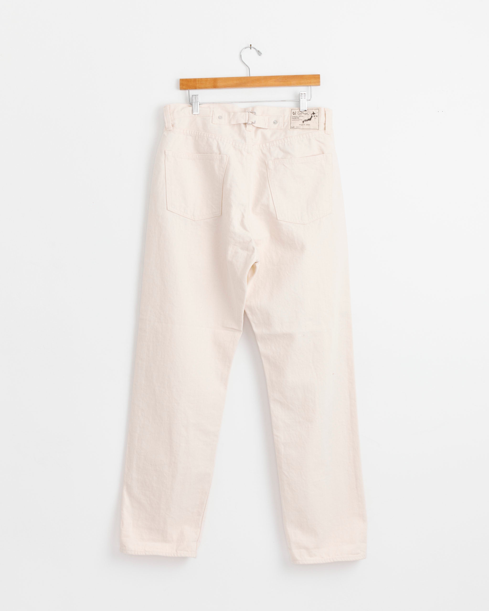 A pair of orSlow Grand Dad's Fit Kinari Pant in Ecru, high-waisted with a straight-leg cut and two back pockets, inspired by vintage workwear, shown on a wooden hanger against a plain white background.