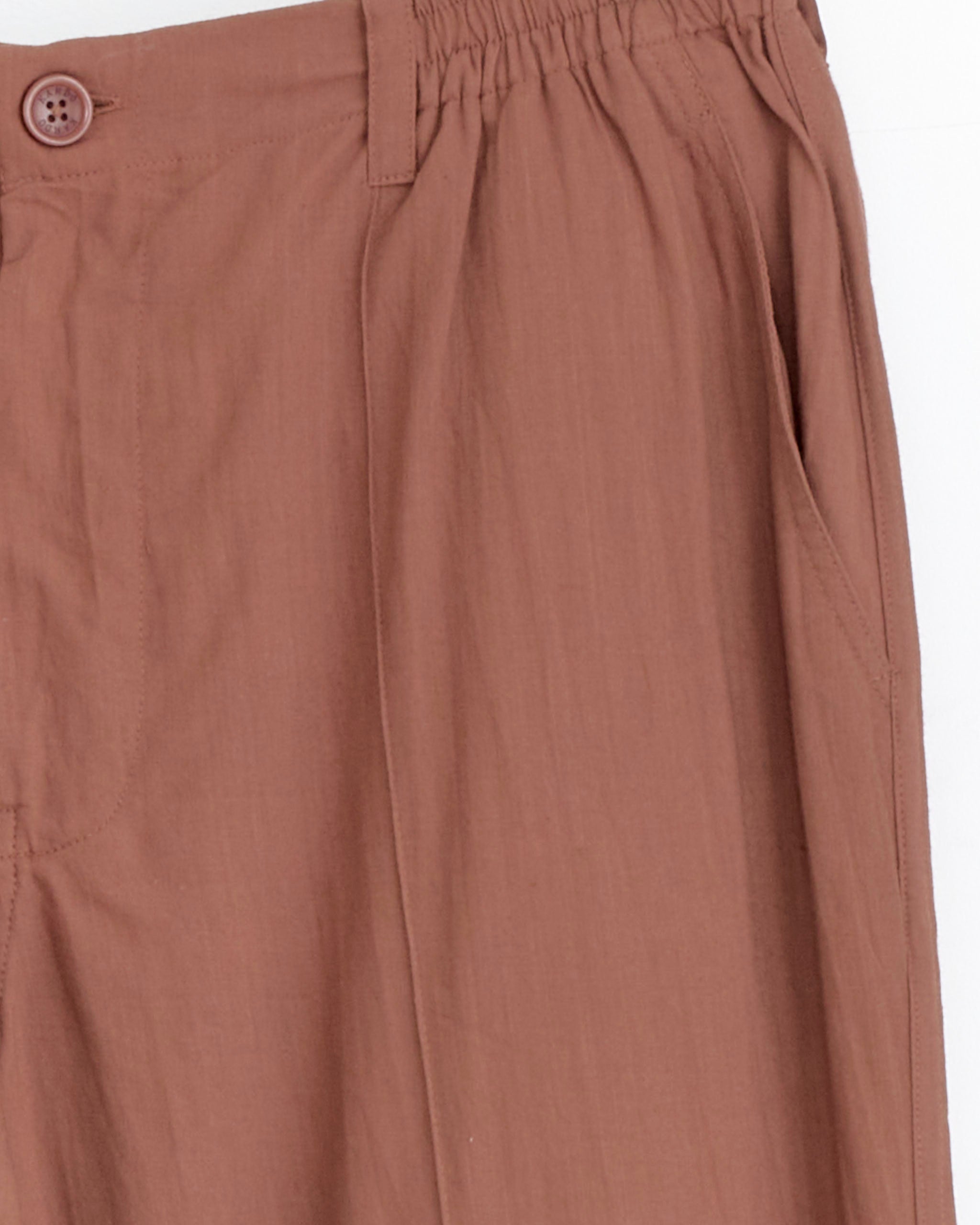 Close-up of the upper section of Kardo's Kedar Trouser in Ganache, highlighting an elastic waistband, button closure, and side pocket detail against a light background.