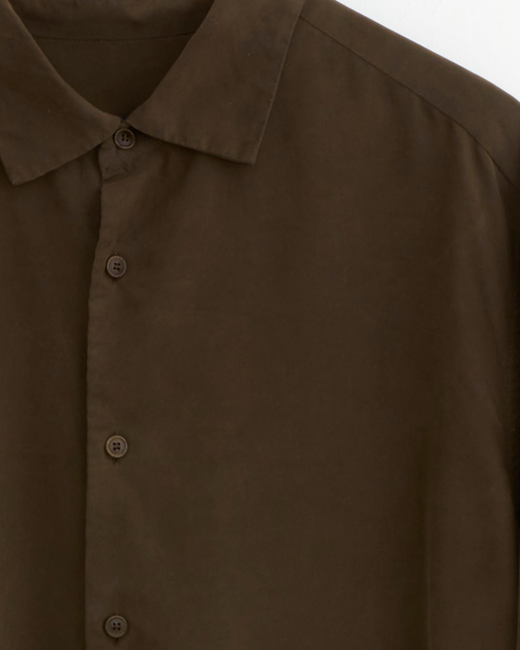 A close-up of the Casey Casey Big Raccourice Shirt in Brown, featuring the collar, upper left section, and several buttons; the shirt is crafted from smooth paper cotton.