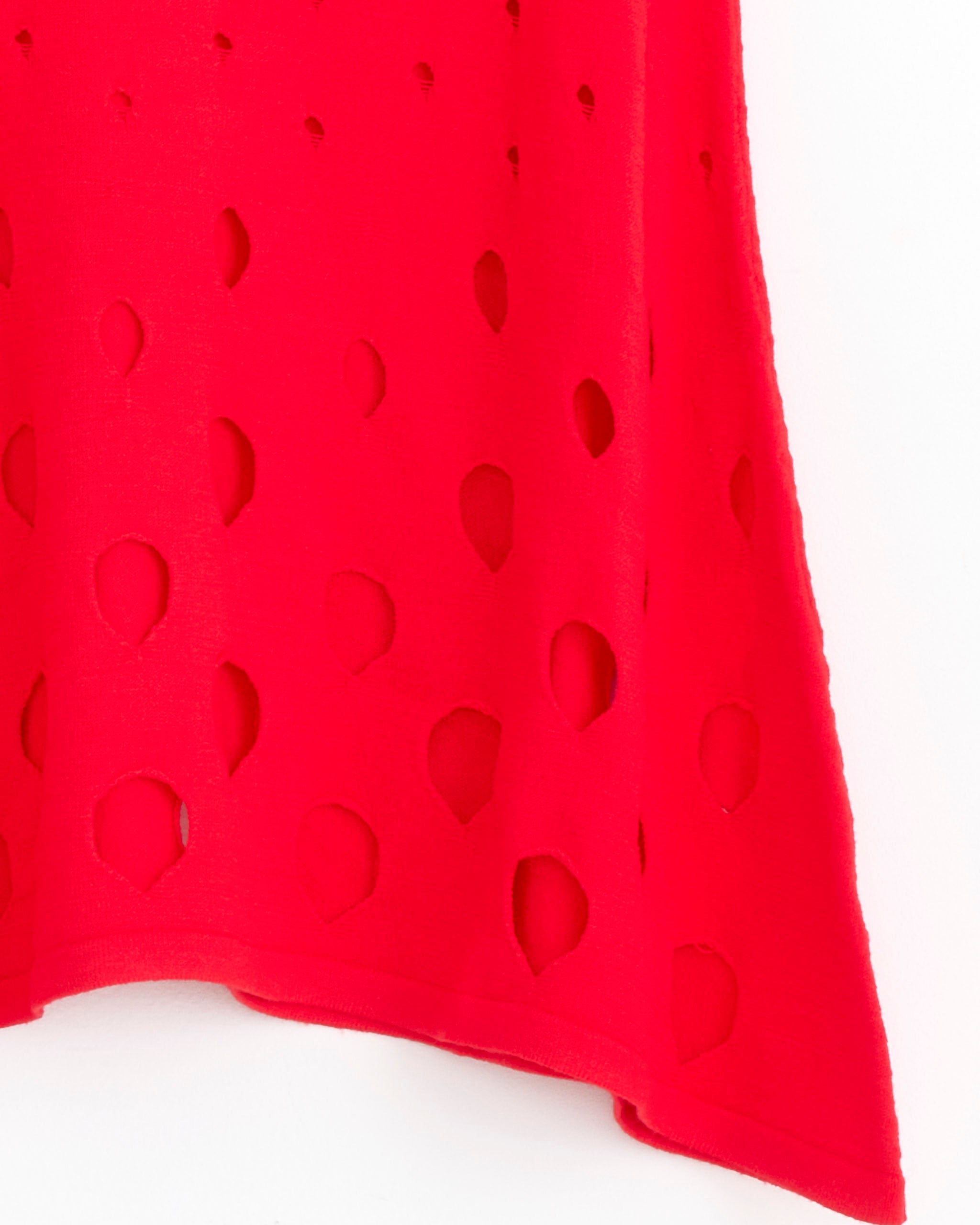 A close-up of the Gimaguas Aros Skirt in Red, featuring bright red textured fabric with an uneven hem and large teardrop-shaped cutouts arranged in irregular rows.
