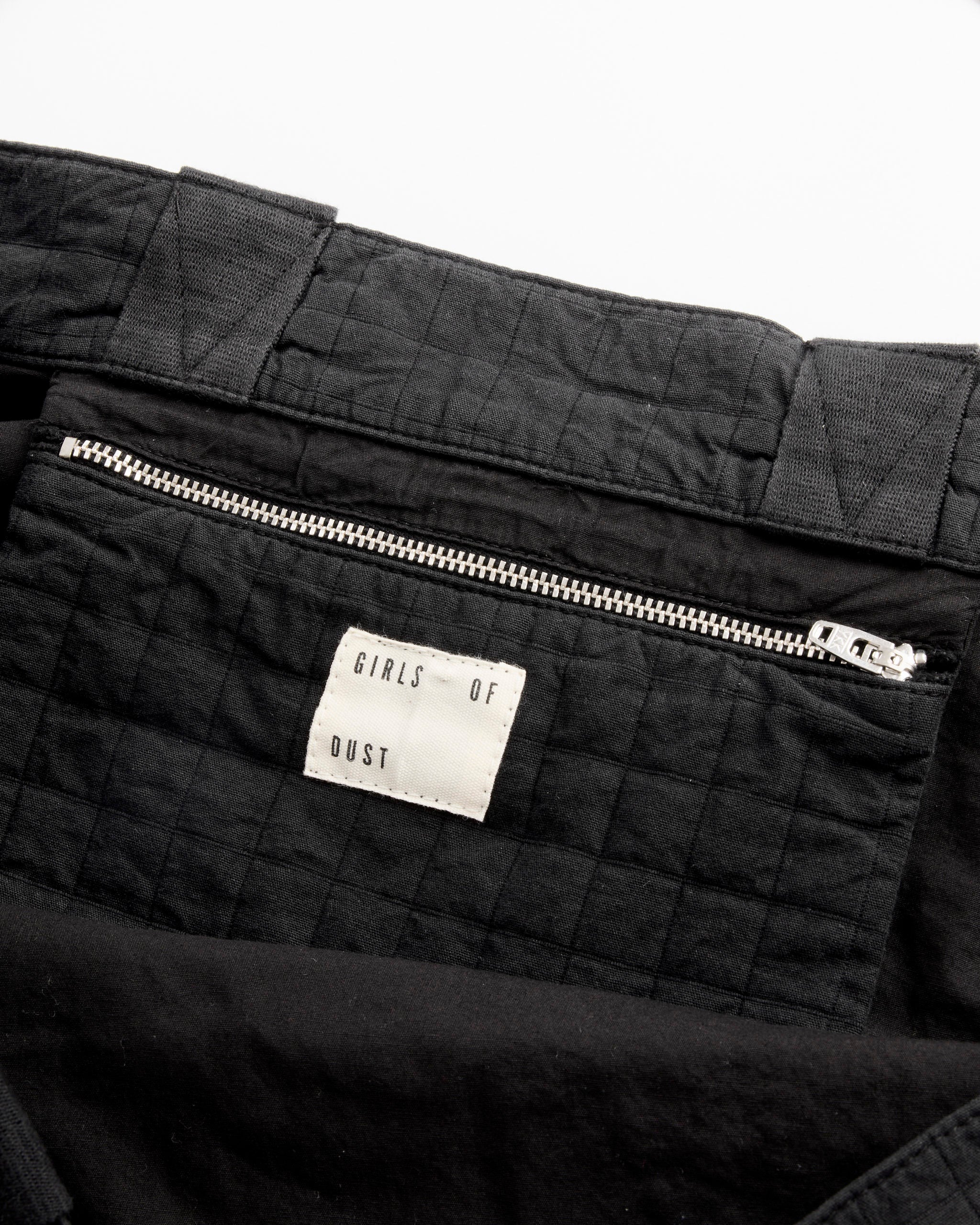 Close-up of the Moon Bag in Black by Girls of Dust, featuring quilted cotton fabric, a zippered pocket with a white brand label, and detailed stitching that highlights the bag’s textured design.