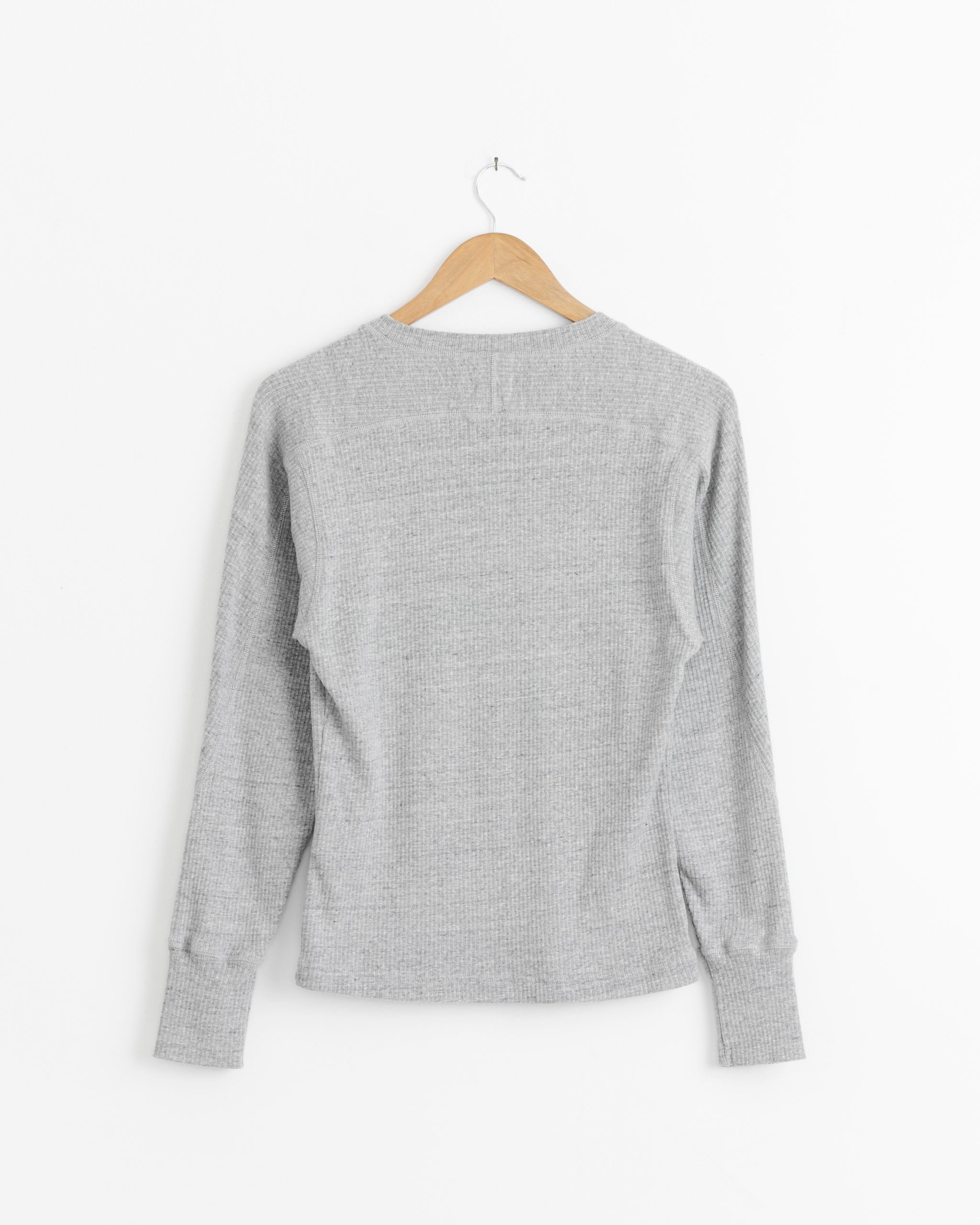 The Girls of Dust Button Down Cardigan in Grey Melange is shown on a wooden hanger against a plain white background, displayed from the back.