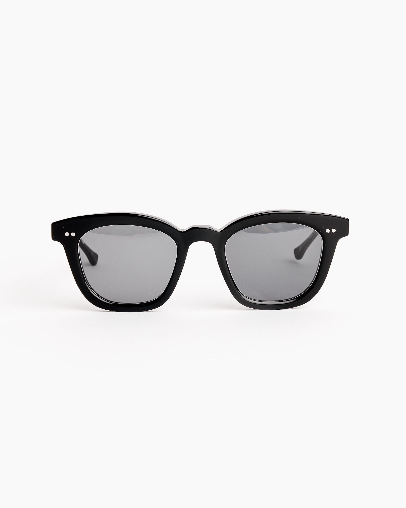 A pair of Native Sons Kowalski 2 Sunglasses in Black/White Gold/GR-9 Dark Grey, featuring dark lenses and silver detailing on the frame corners, displayed on a white background.