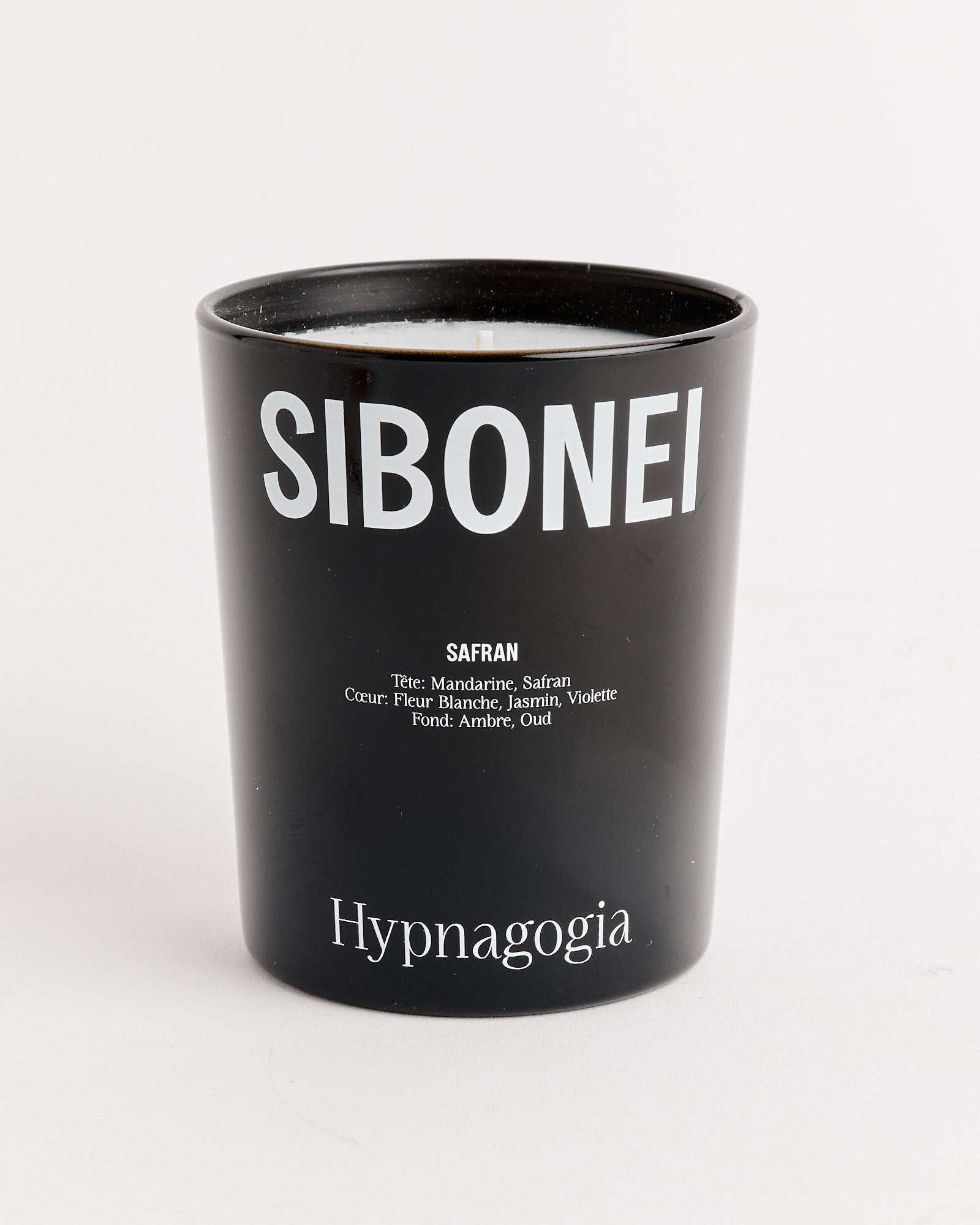 A black SIBONEI Hypnagogia (Safran) candle with bold white branding, scent notes underneath, and "Hypnagogia" at the base. Features white soy wax and a single cotton wick.